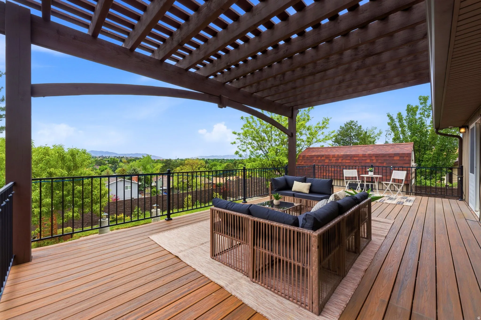 Expansive outdoor deck featuring wood-finish flooring and a partial pergola overhead