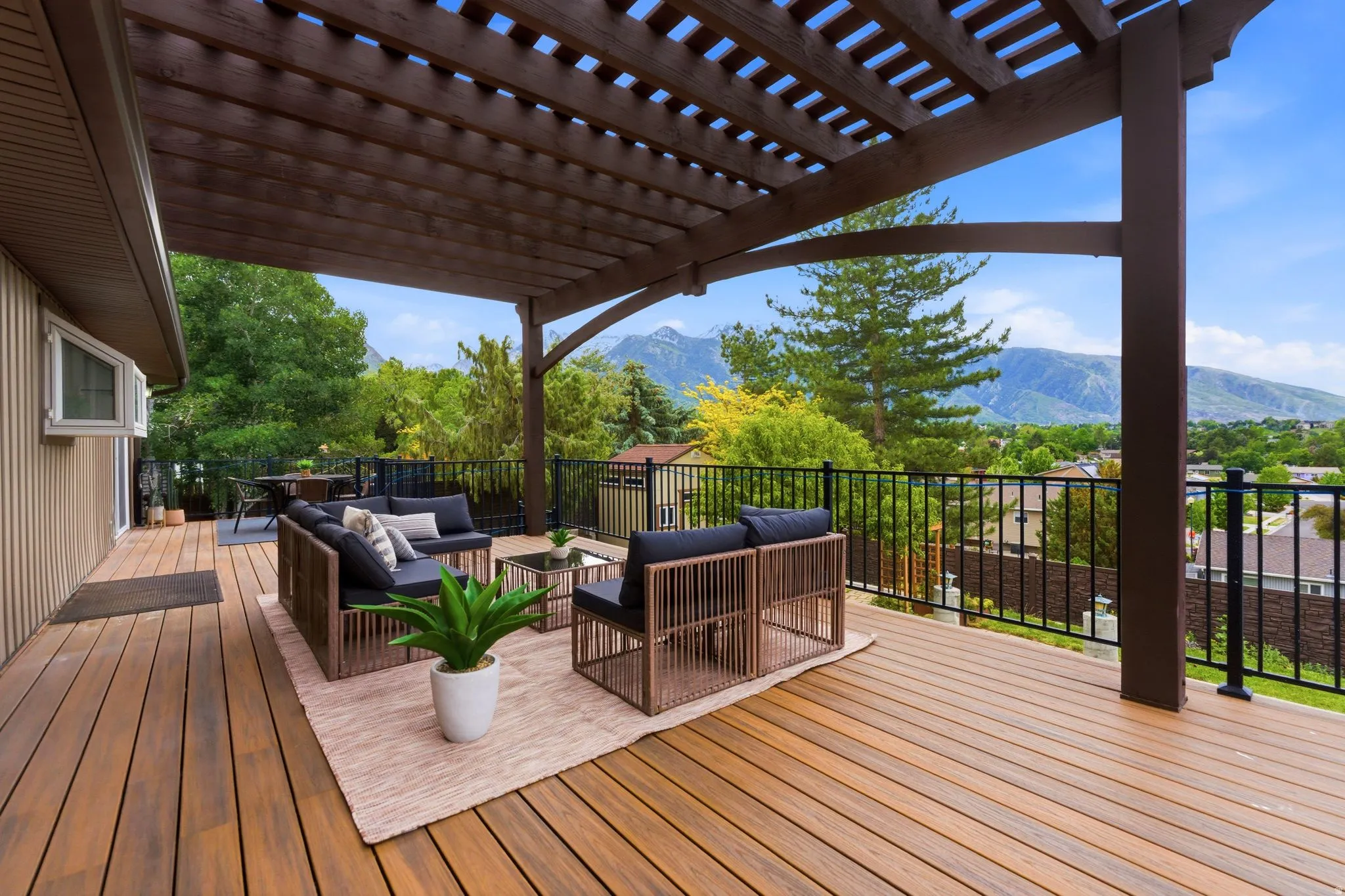 Expansive wood-finish deck with a large pergola featuring beautiful mountain views.