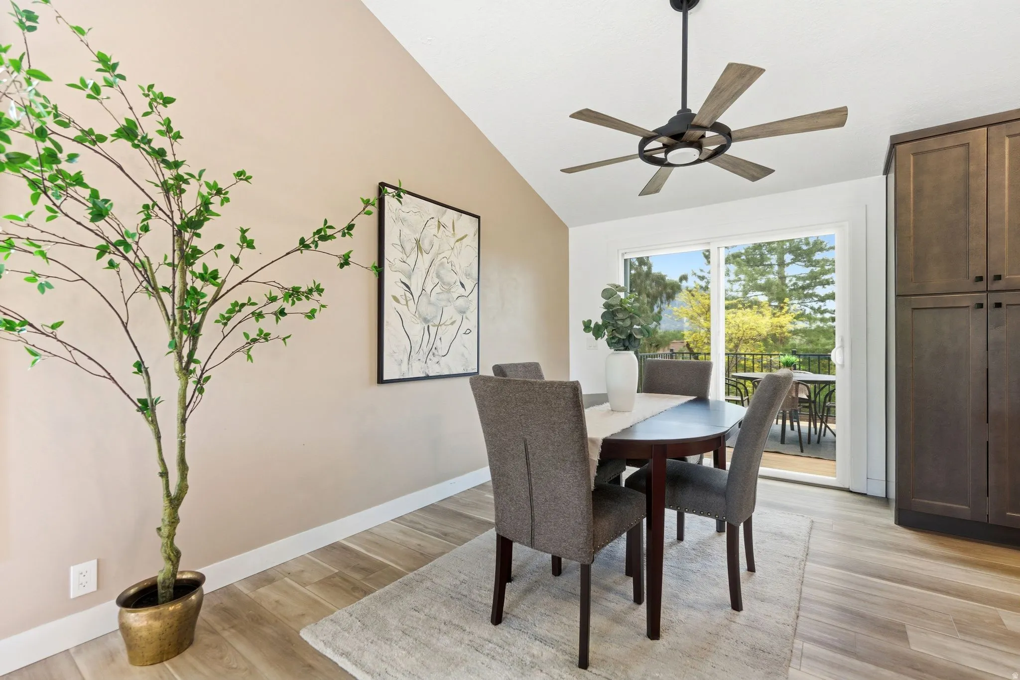 Dining area featuring wood-finish flooring, vaulted ceiling, and a modern ceiling fan