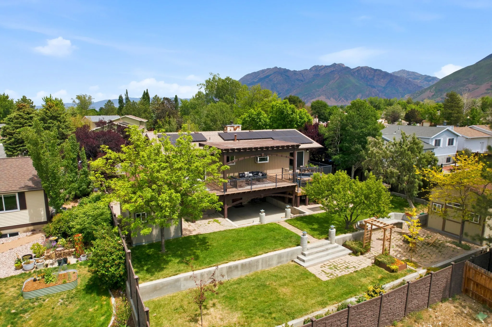 Multi-level dwelling featuring a spacious outdoor deck, integrated solar panels, and a terraced backyard with a lawn area