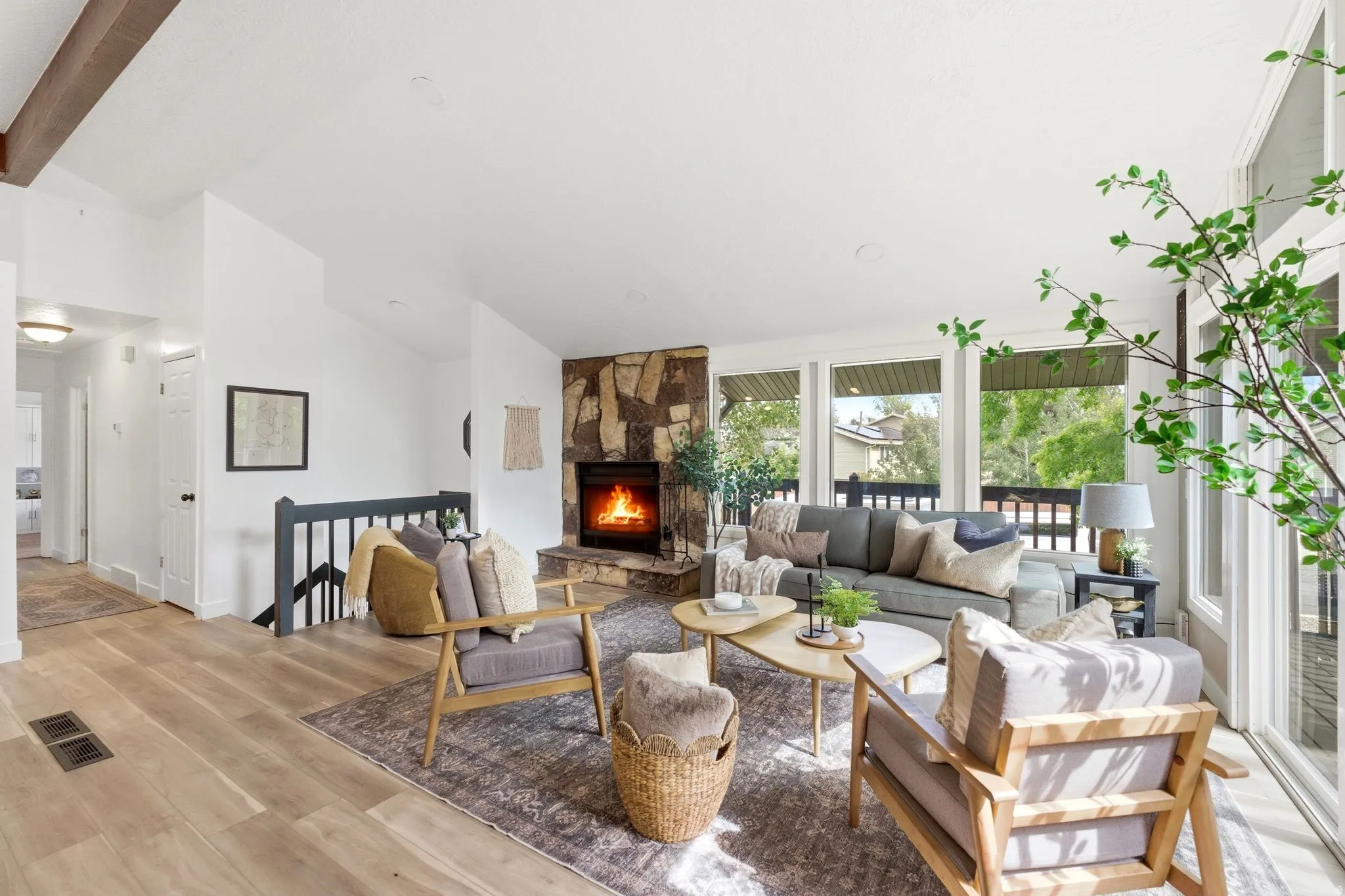 Living area featuring a stone-clad fireplace, wood-finish flooring, and vaulted ceilings with exposed beams