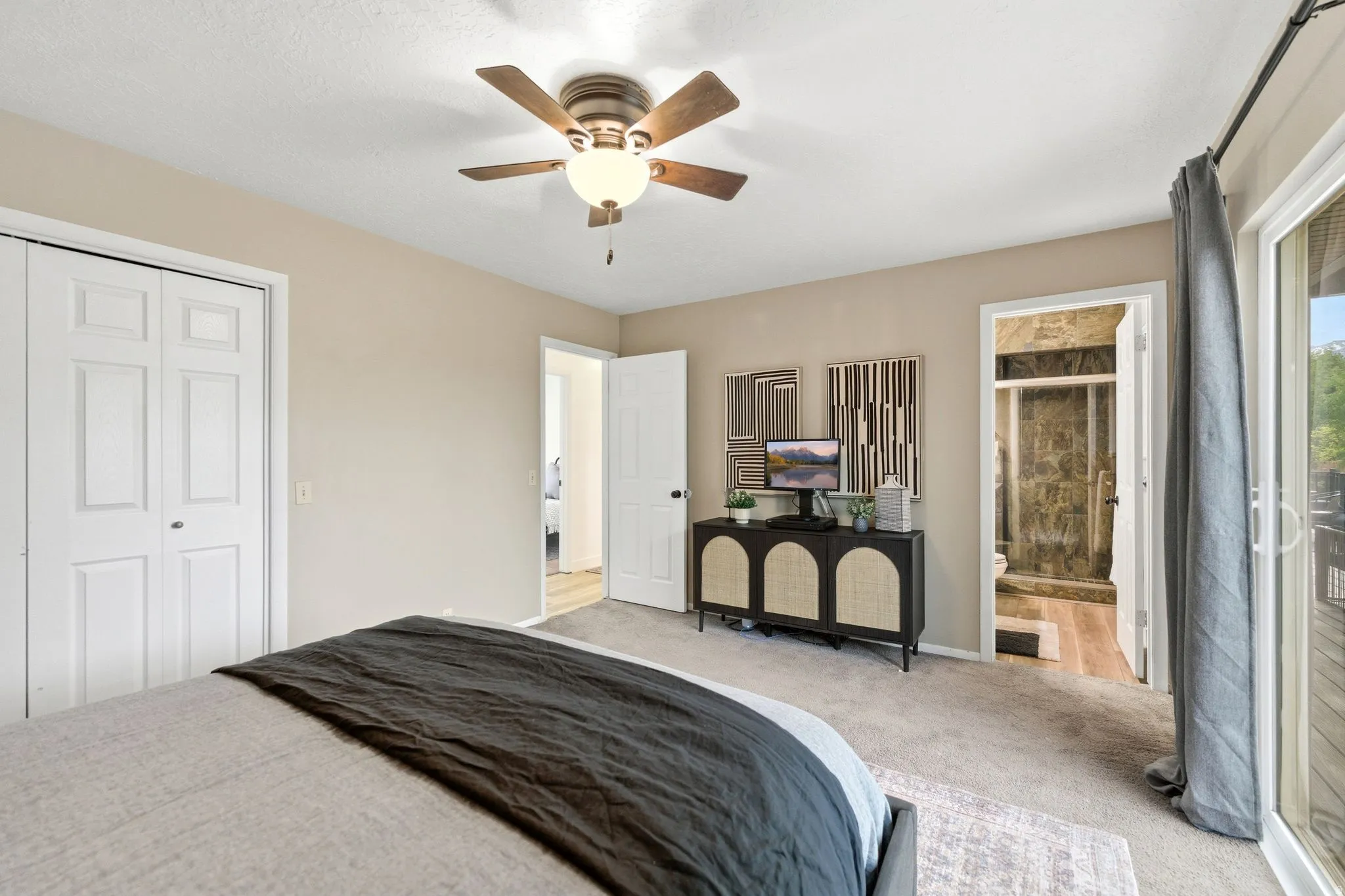 Primary bedroom with neutral carpeting and a ceiling fan with integrated lighting
