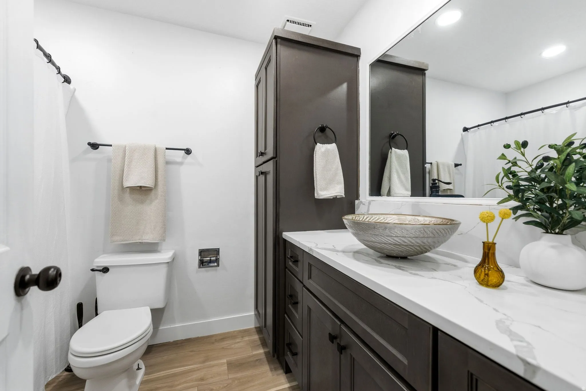 Bathroom featuring a dark wood-finish vanity with a vessel sink, a white countertop, and a built-in storage cabinet