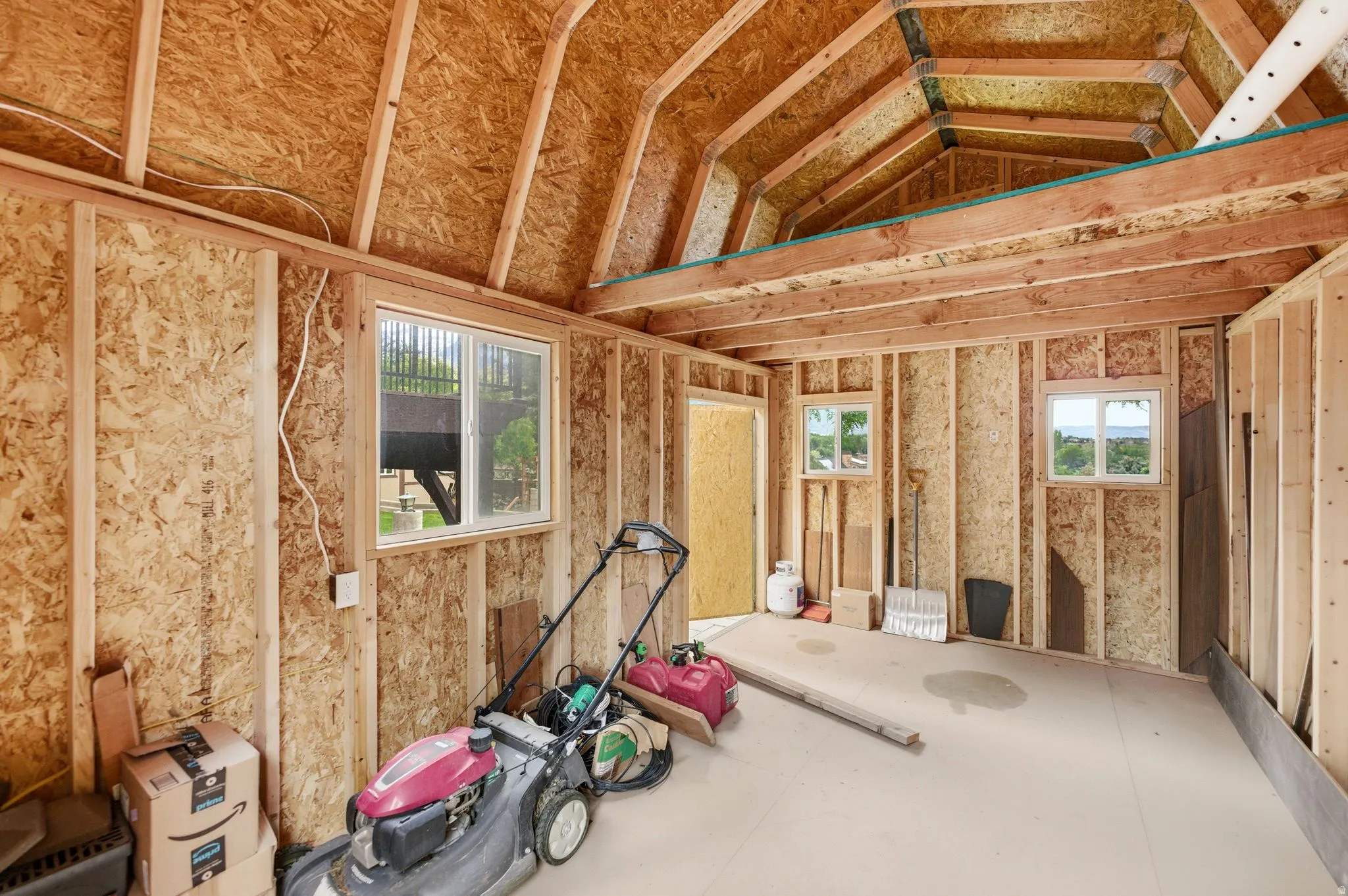 Unfinished interior space of shed featuring exposed wood framing and oriented strand board walls