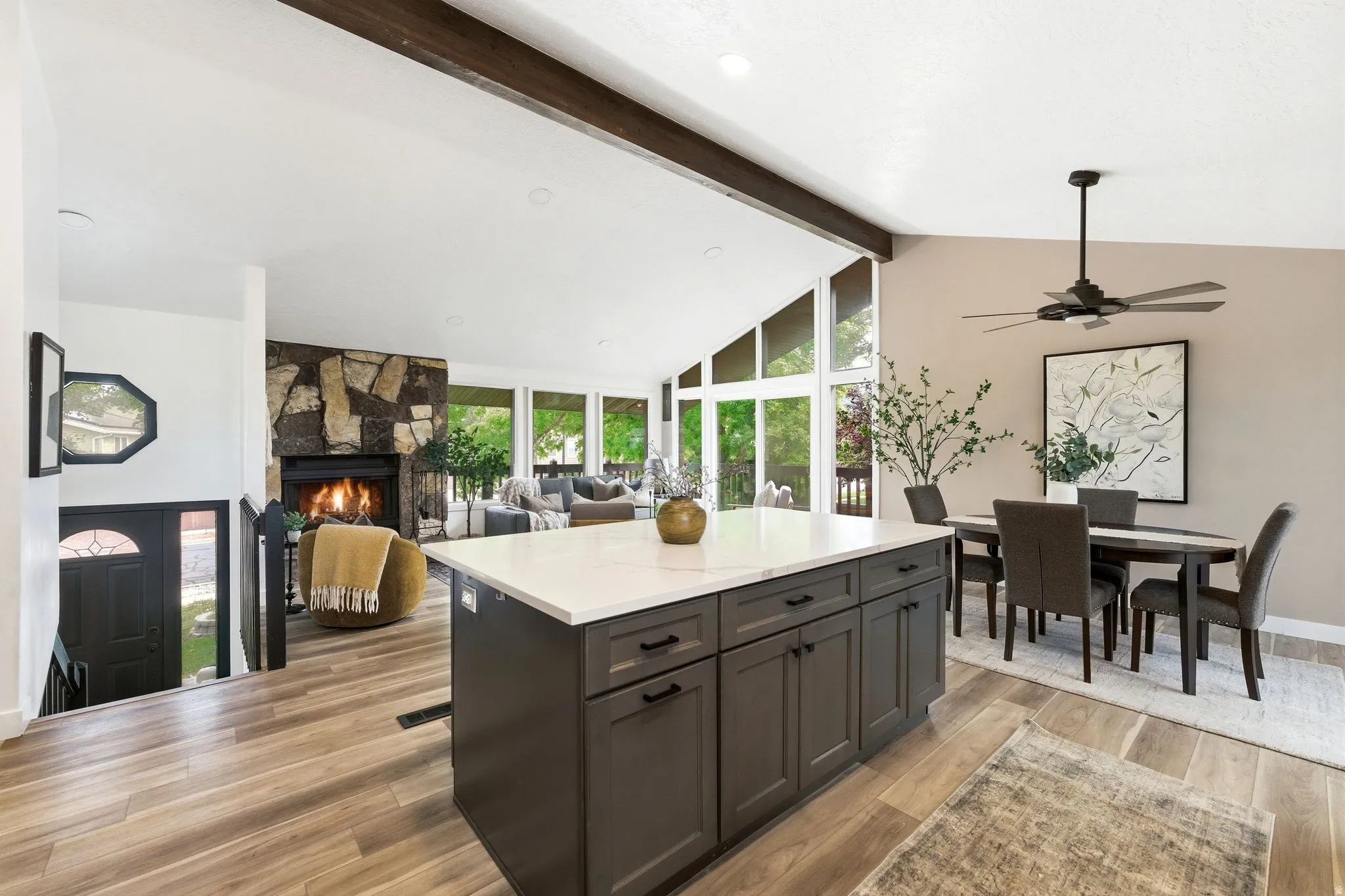 Spacious open-concept living area featuring wood-finish flooring and a vaulted ceiling with exposed beam accents