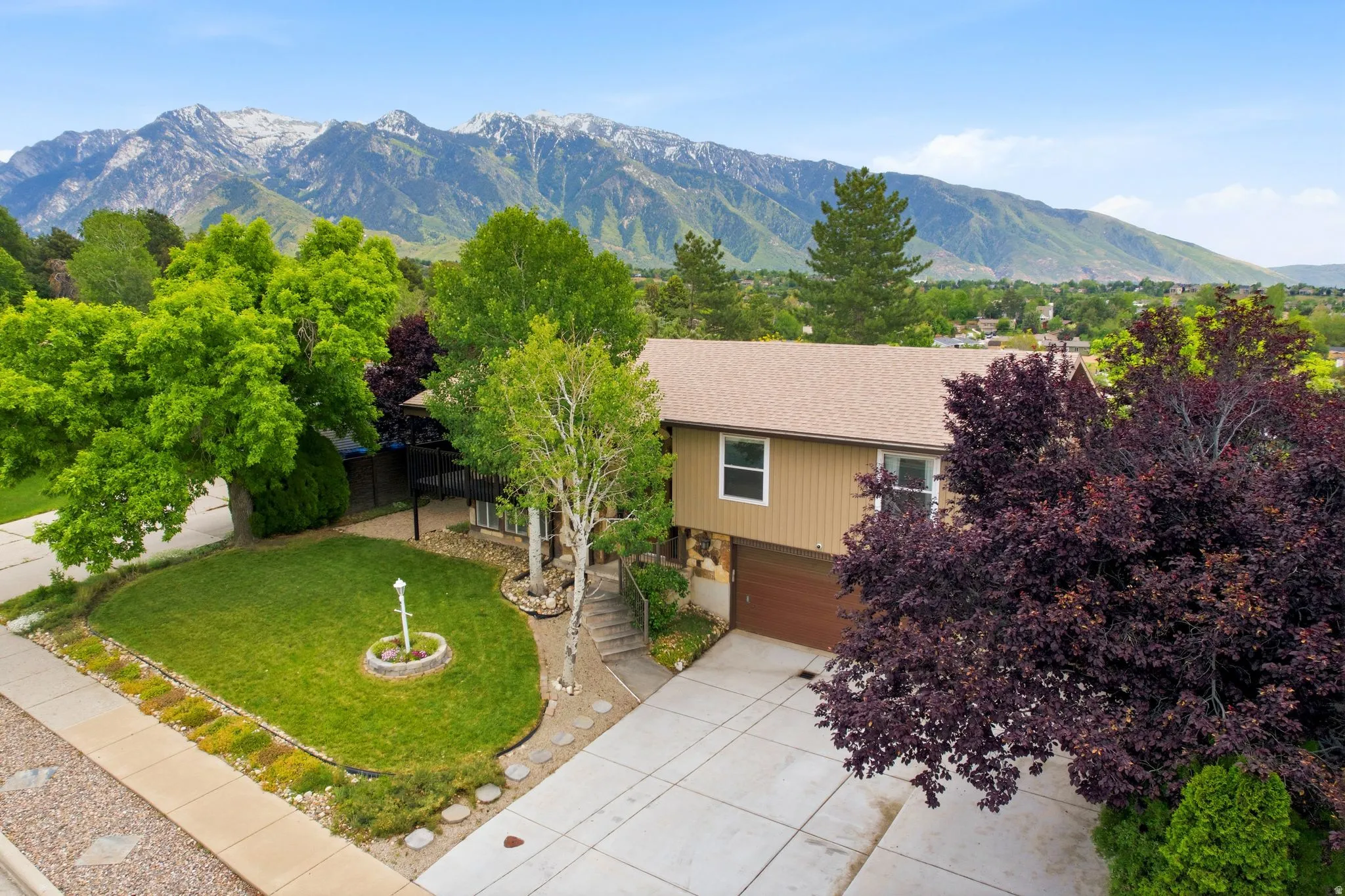 Split-level residence featuring a two-car garage, concrete driveway, and established landscaping