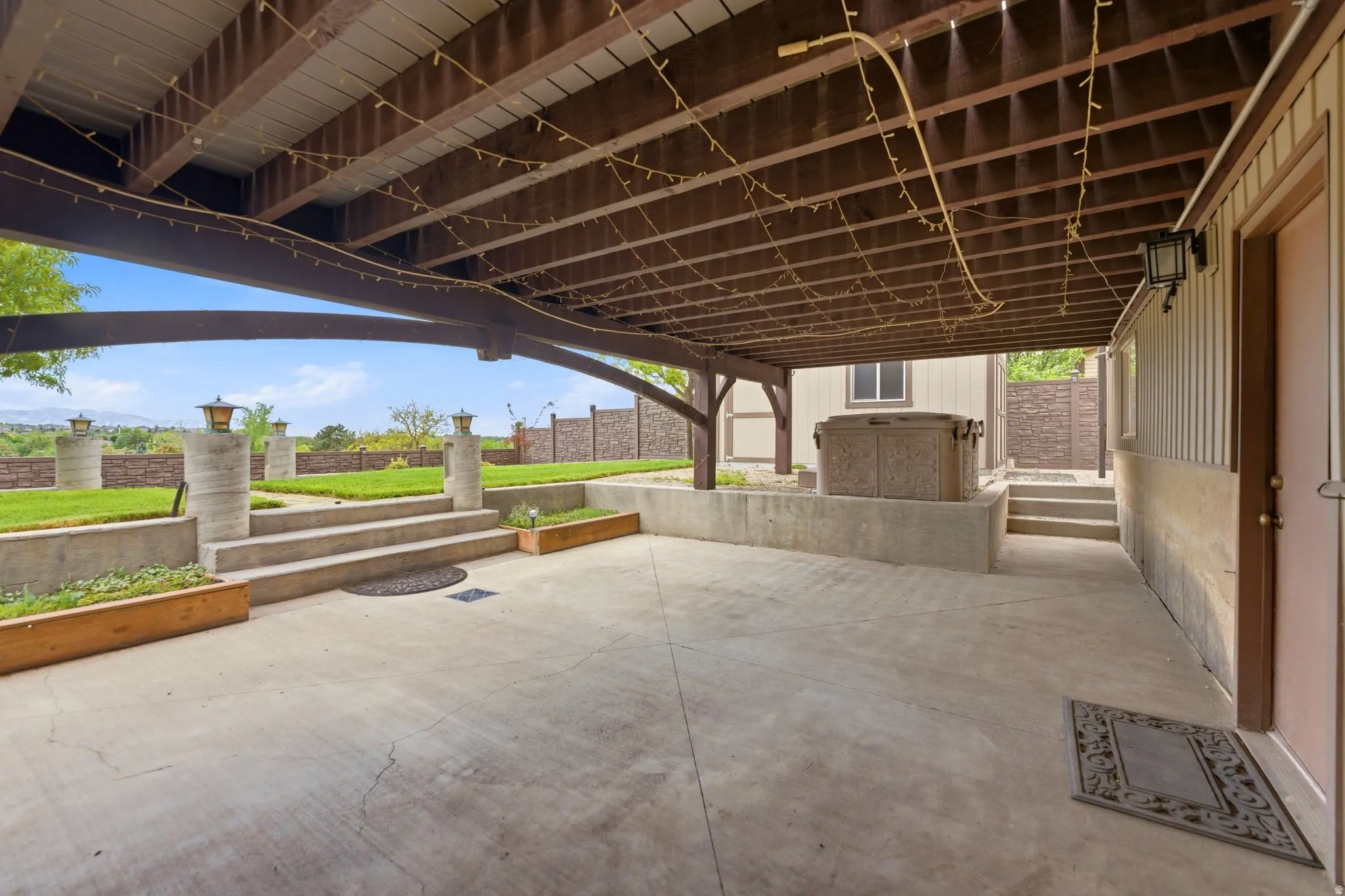 Covered concrete patio with exposed wood ceiling beams and hot tub