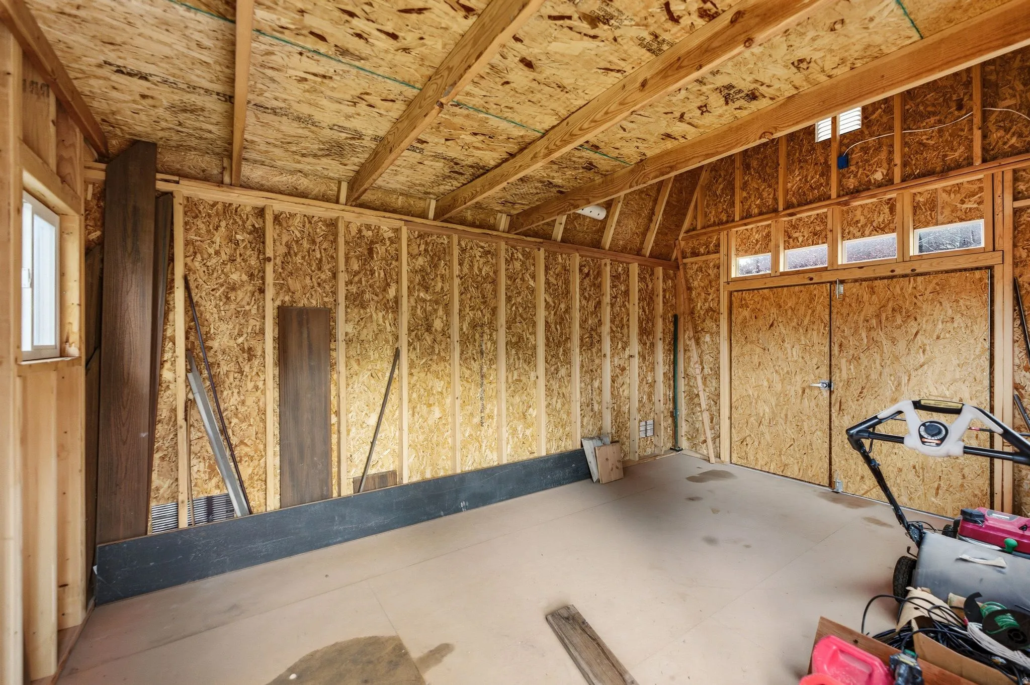Unfinished interior space of shed featuring exposed wood framing and oriented strand board walls