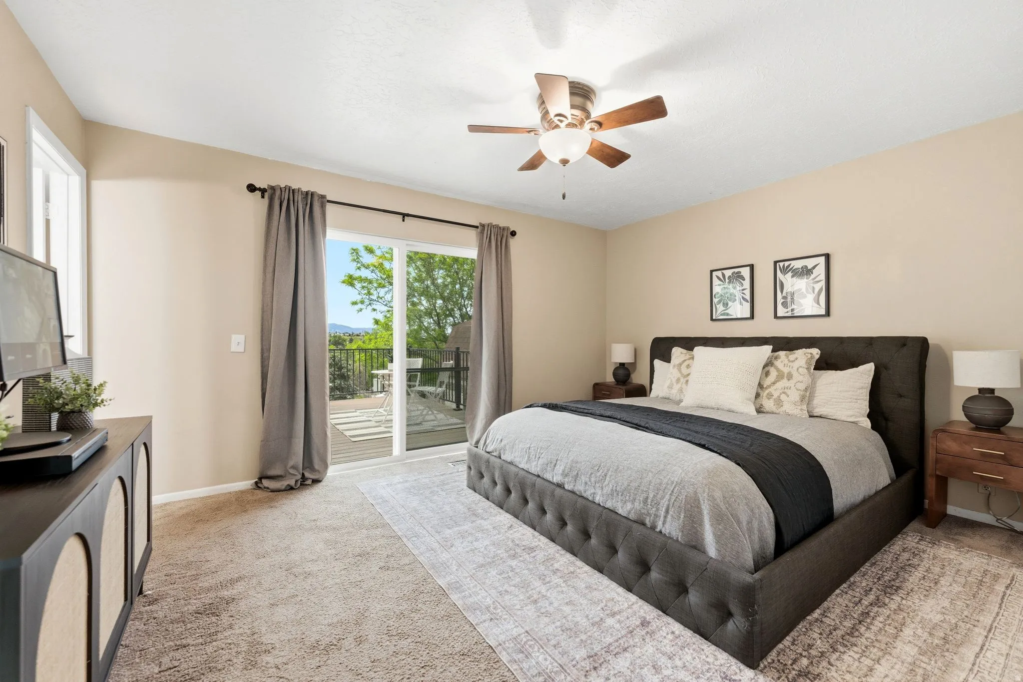 Spacious primary bedroom featuring neutral wall tones, carpeted flooring, and a ceiling fan with integrated lighting