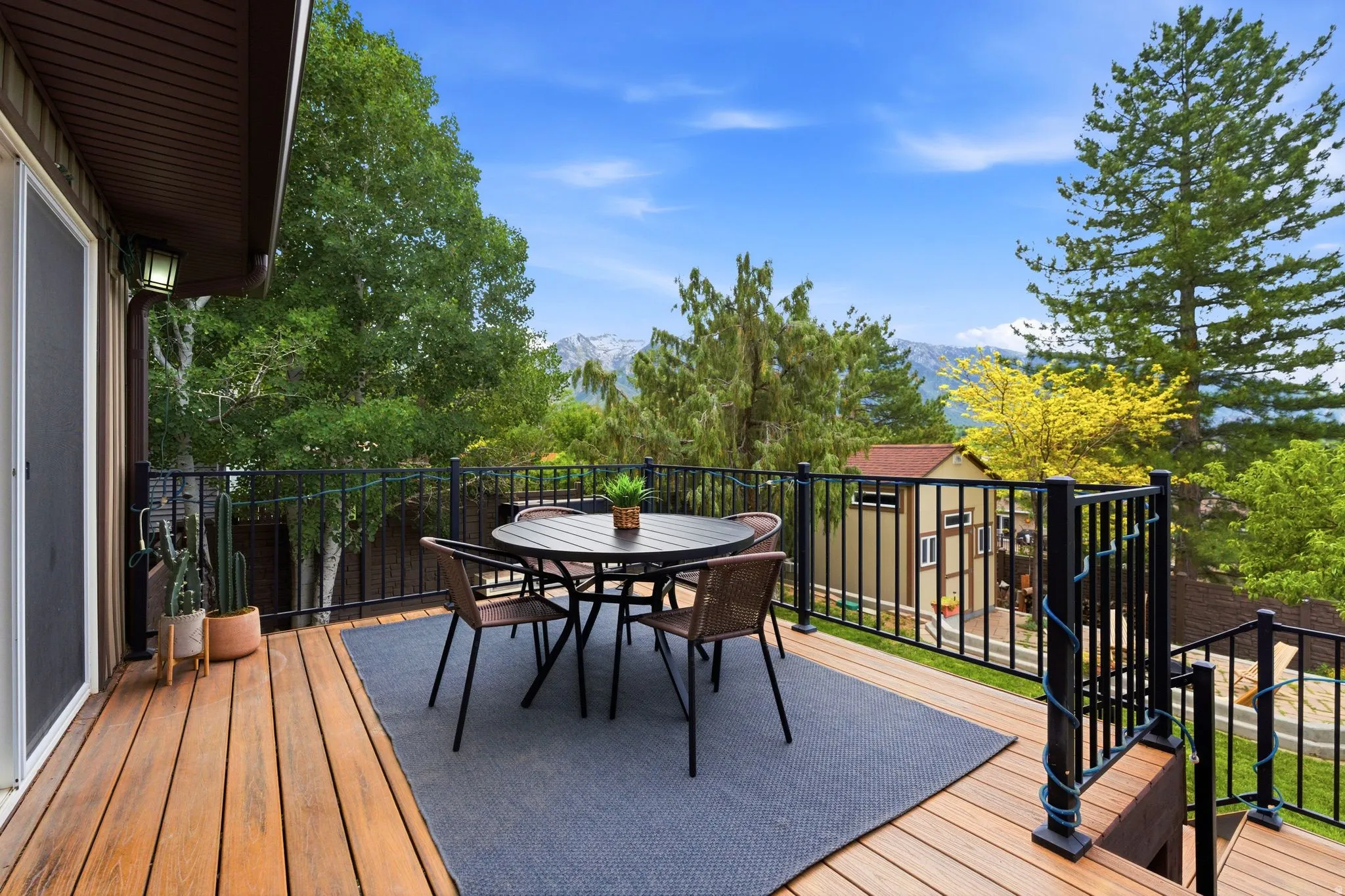 Expansive outdoor deck featuring wood-finish flooring, black metal railings, and a sliding glass door