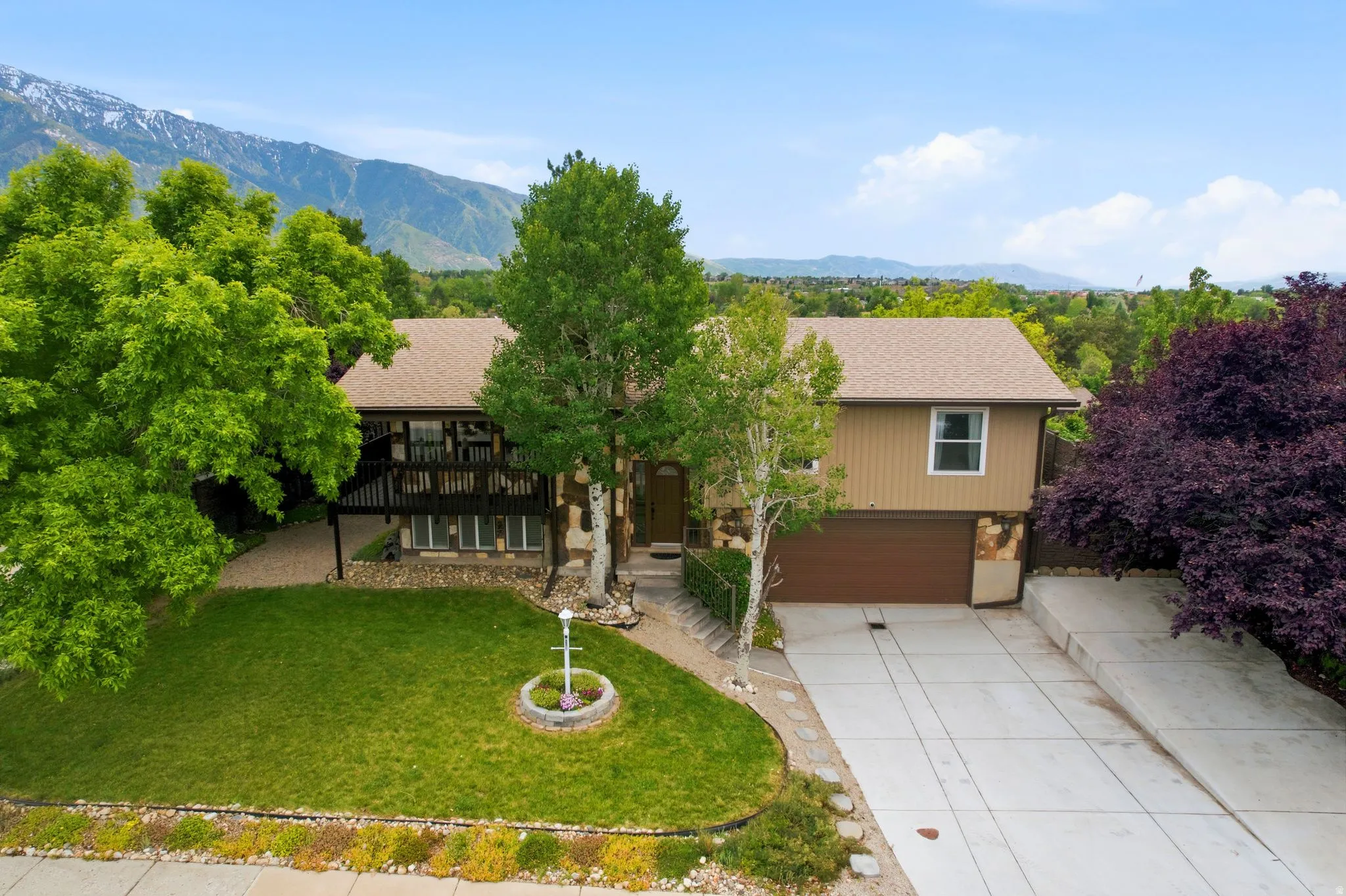 Split-level residence featuring a mountain backdrop, a brown facade, and a multi-level deck