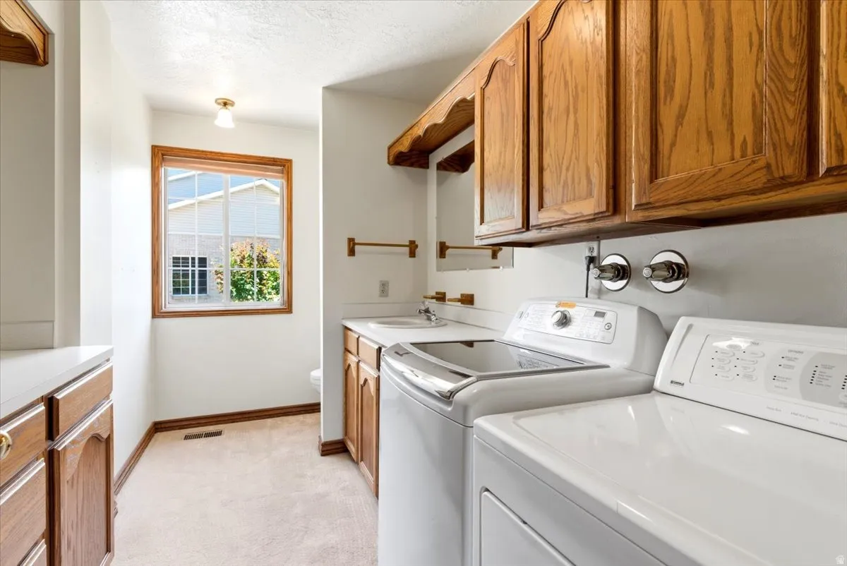 Laundry area featuring wood cabinetry, white countertops, built-in sink, and window with exterior exposure
