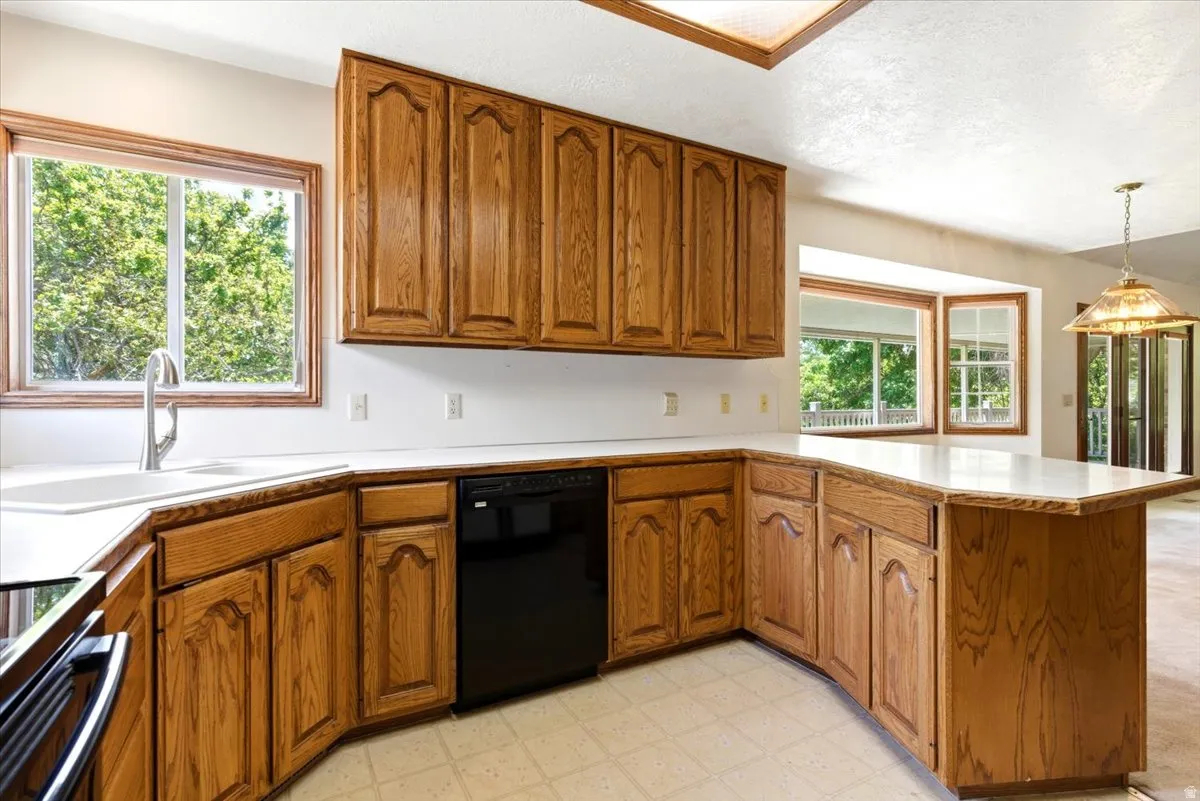 Kitchen featuring wood cabinetry, white countertops, a black dishwasher, and a stainless steel sink with a gooseneck faucet