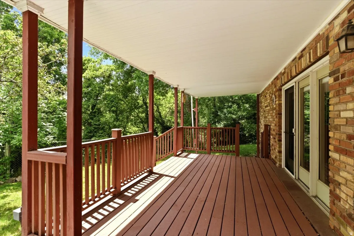 Expansive covered deck featuring wood-finish flooring and a full railing system