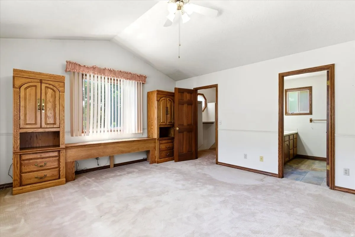 Spacious room featuring vaulted ceilings, a ceiling fan, and carpeted flooring