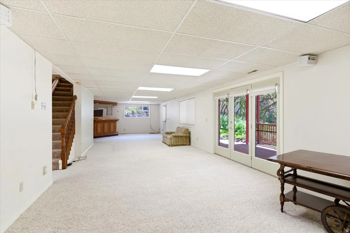 Spacious interior room featuring light-colored carpeting and a drop ceiling with recessed lighting