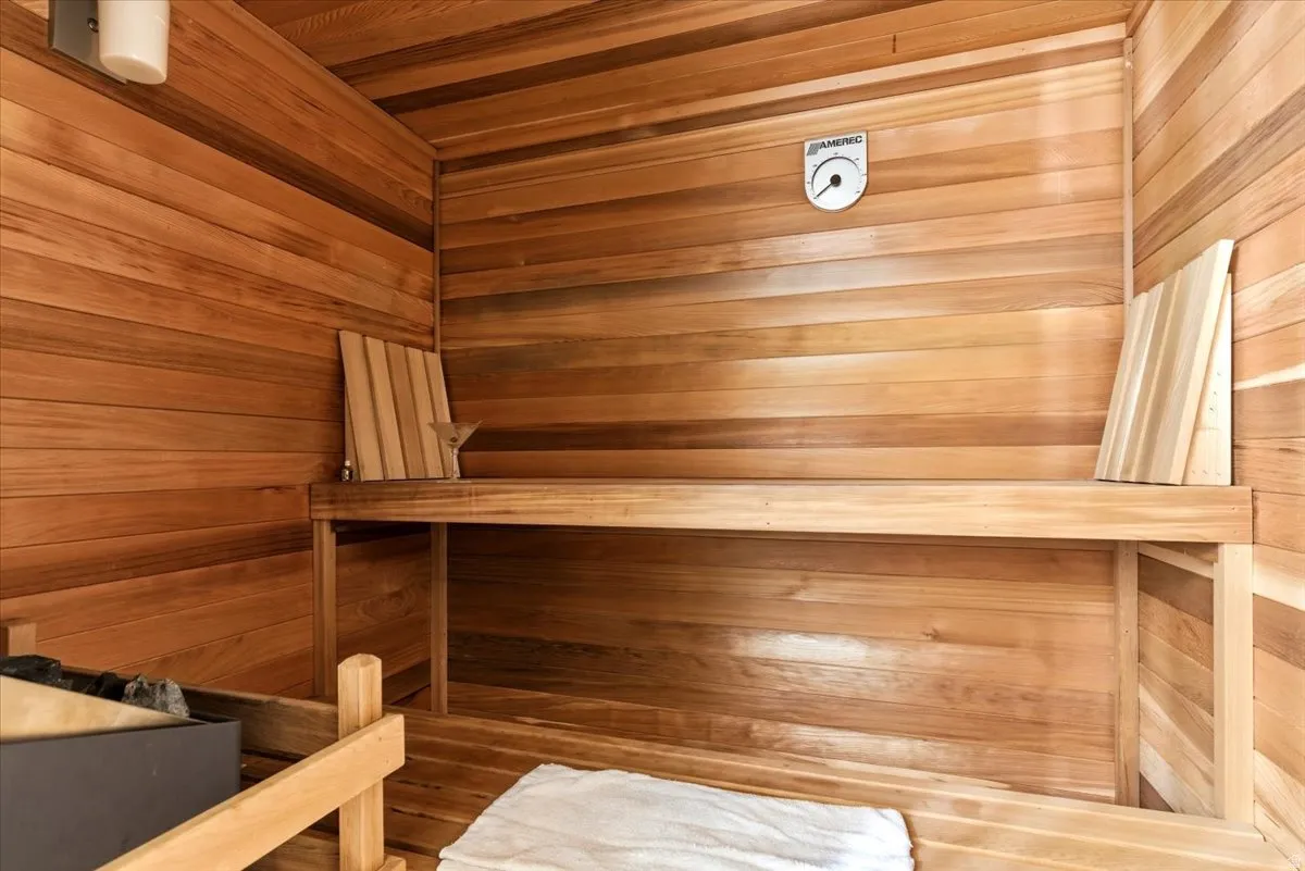 Built-in sauna featuring horizontal wood paneling, multi-level wood bench seating, and a wall-mounted thermometer