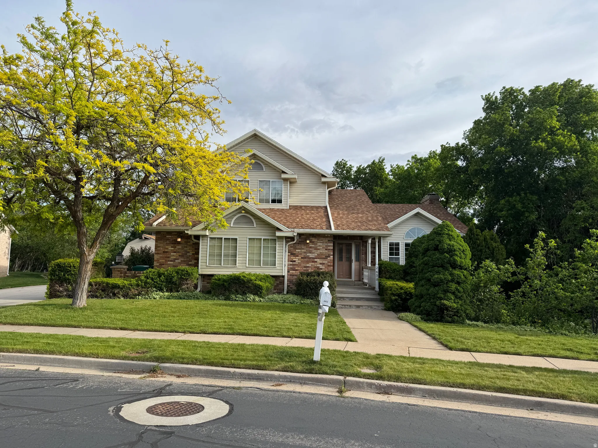 Two-story residence featuring brick and siding exterior, a gabled roofline, and mature landscaping