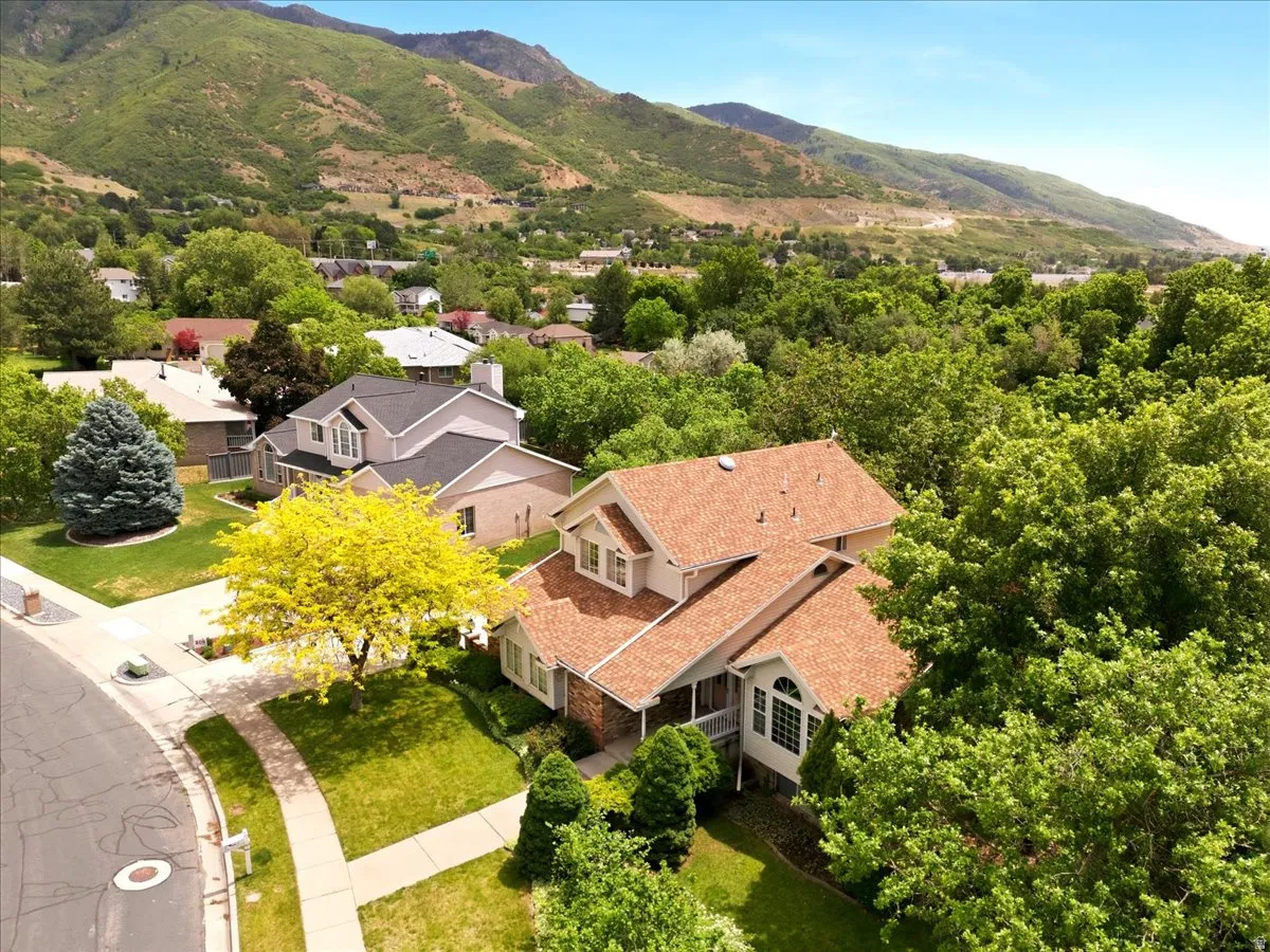 Single-family residence with a mountain backdrop, mature landscaping, and a curved sidewalk