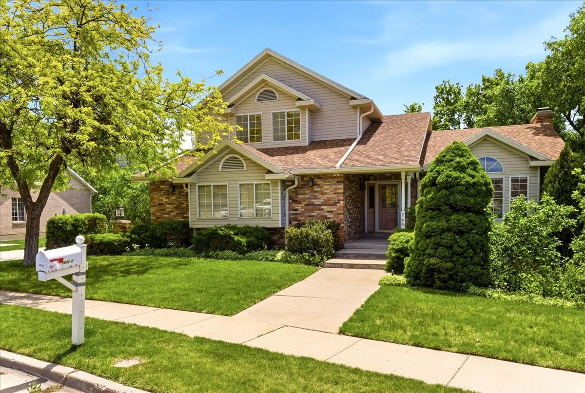 Traditional architectural style home featuring brick and siding accents, a prominent entryway, multiple gables, and a mature tree providing shade