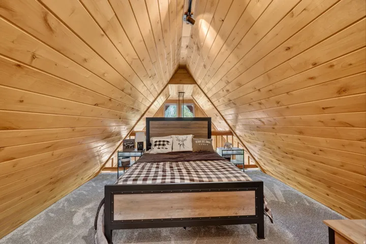 Vaulted wood-paneled ceiling with track lighting, complementing wood-finish side tables, and a visible window with natural light