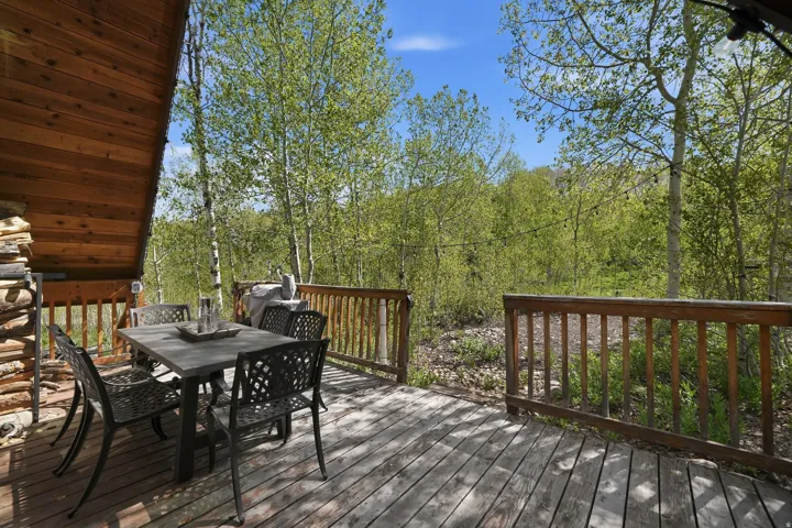 Expansive outdoor deck featuring wood flooring, a wood railing, and a rustic stacked stone accent wall