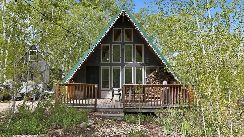 A-frame exterior with a prominent green roofline, featuring a wood-decked front porch with wood railings