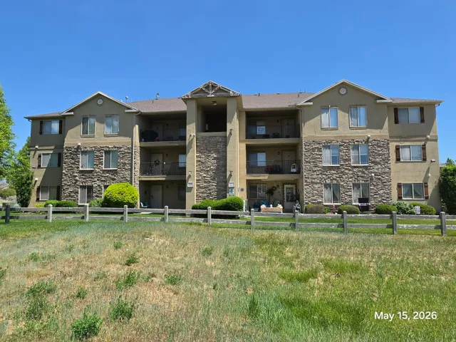 Multi-story residential building featuring a stucco and stone veneer exterior