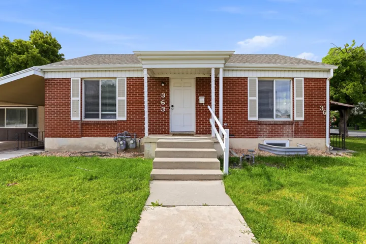 Brick exterior featuring a covered front entry and a concrete walkway