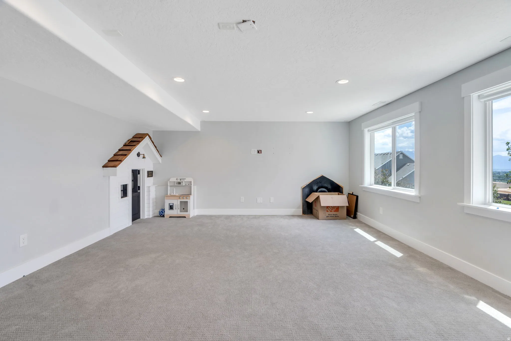 Spacious carpeted room featuring recessed lighting, light gray wall paint, white trim, and two large windows