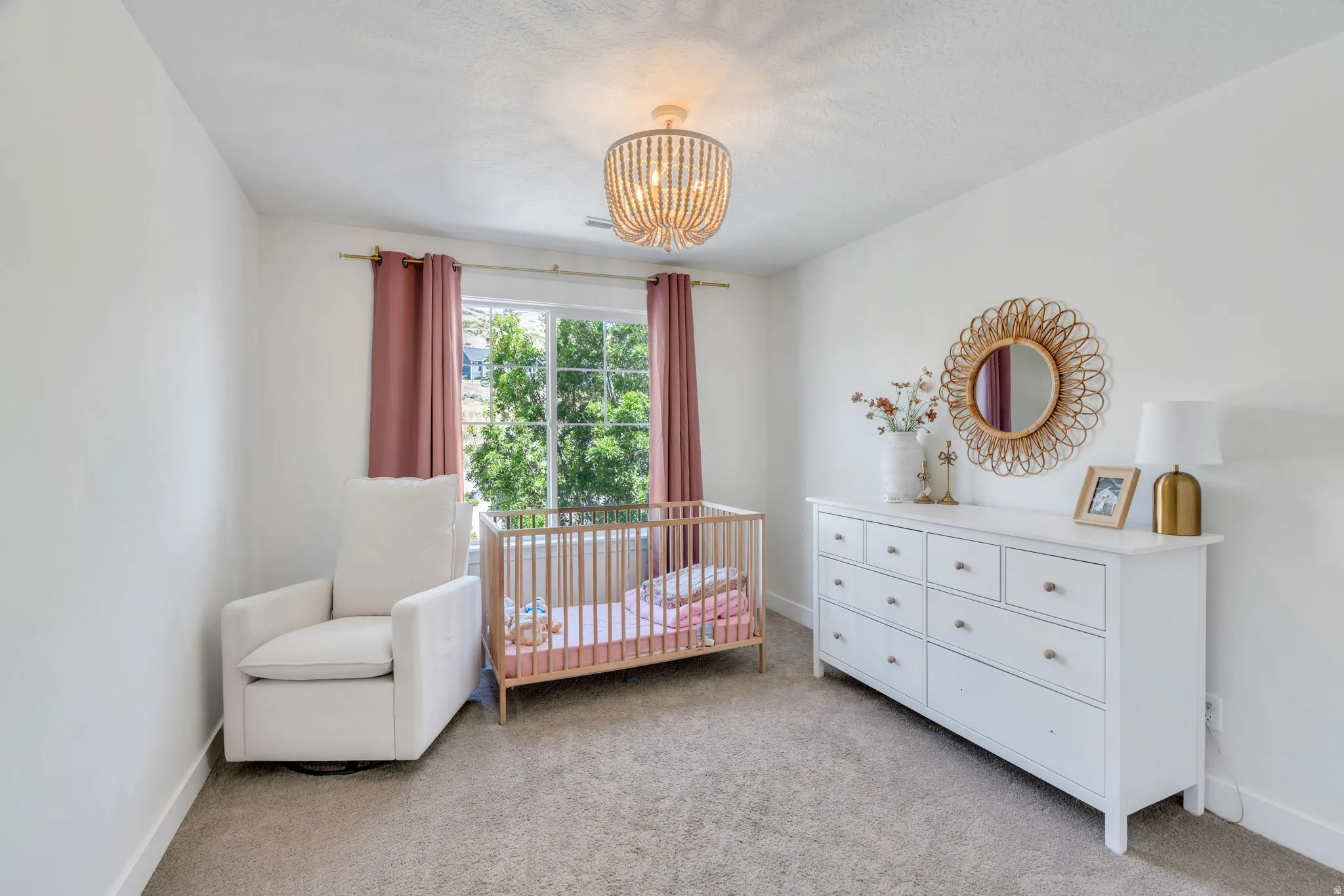 Bright interior space featuring a window with exterior tree foliage, a beaded semi-flushmount light fixture, textured carpeting, and white painted walls