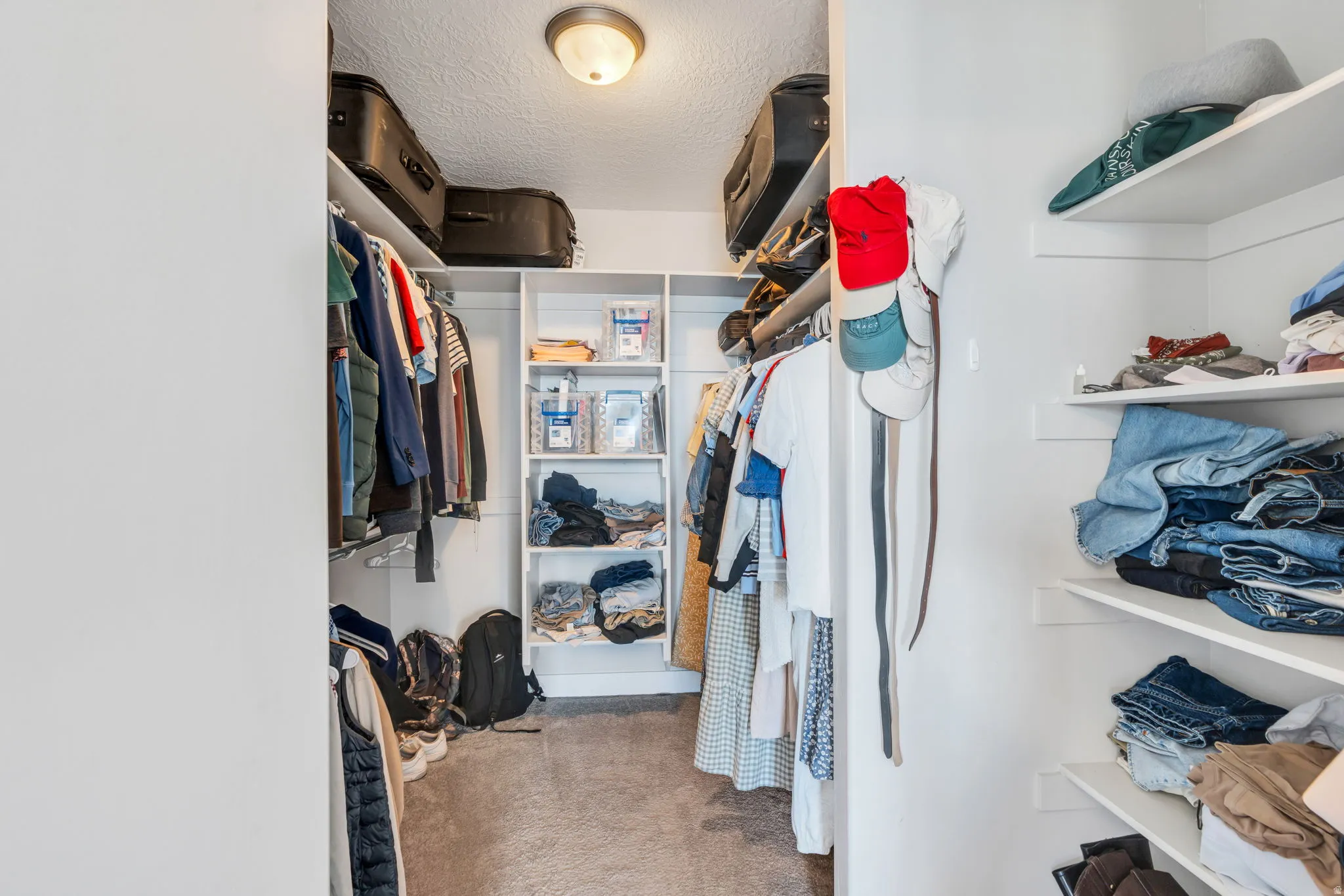 Expansive walk-in closet featuring white built-in shelving, hanging rods, and ample storage space