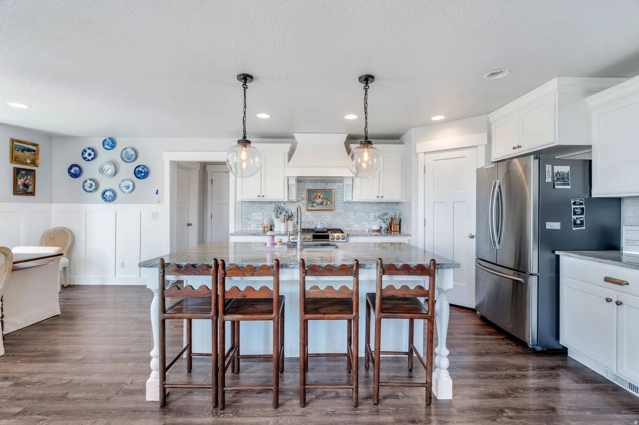 Kitchen featuring a large island with a stone countertop, white shaker cabinetry, stainless steel appliances, and wood-finish flooring