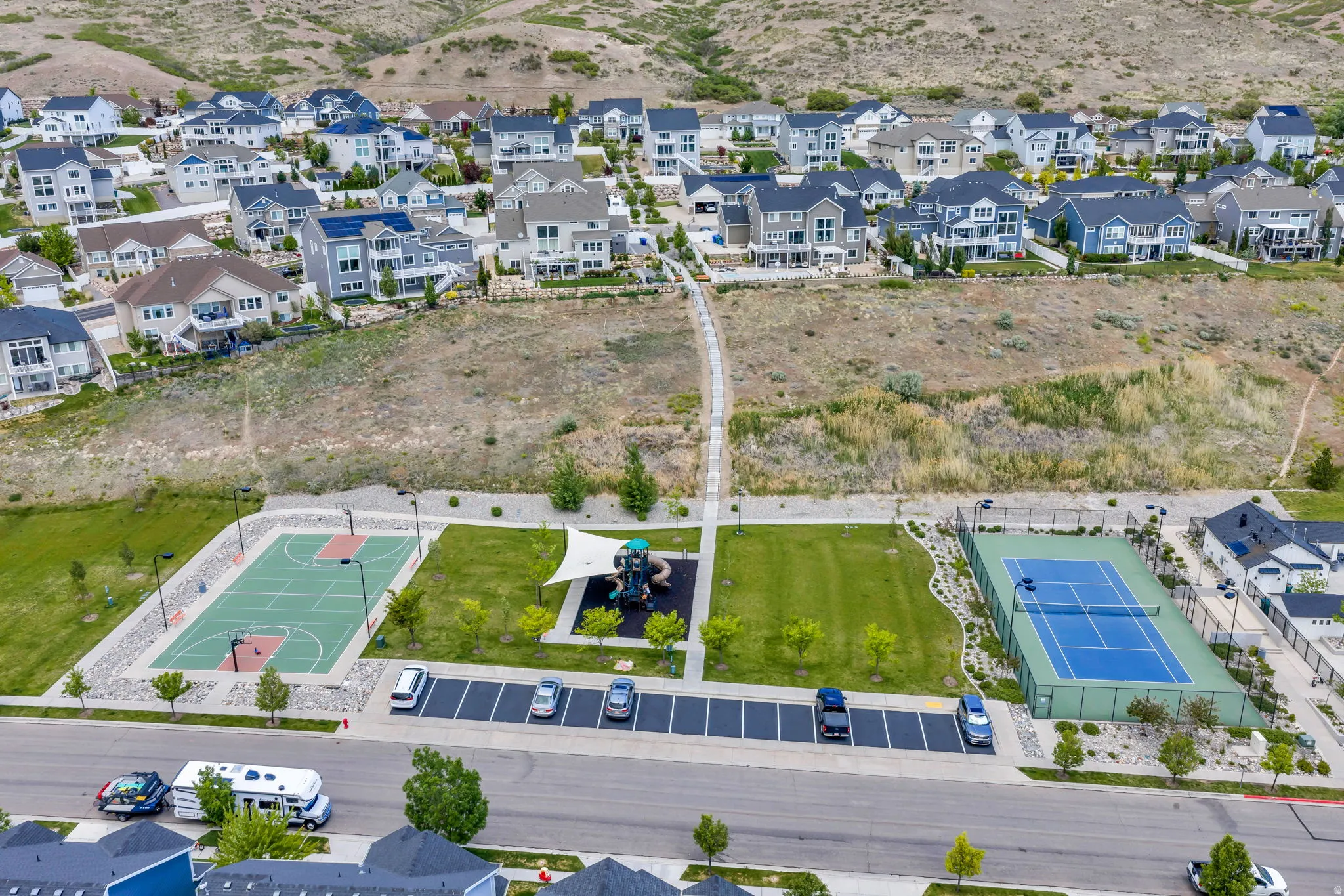 Community park featuring a tennis court, basketball court, and playground area with shade structure