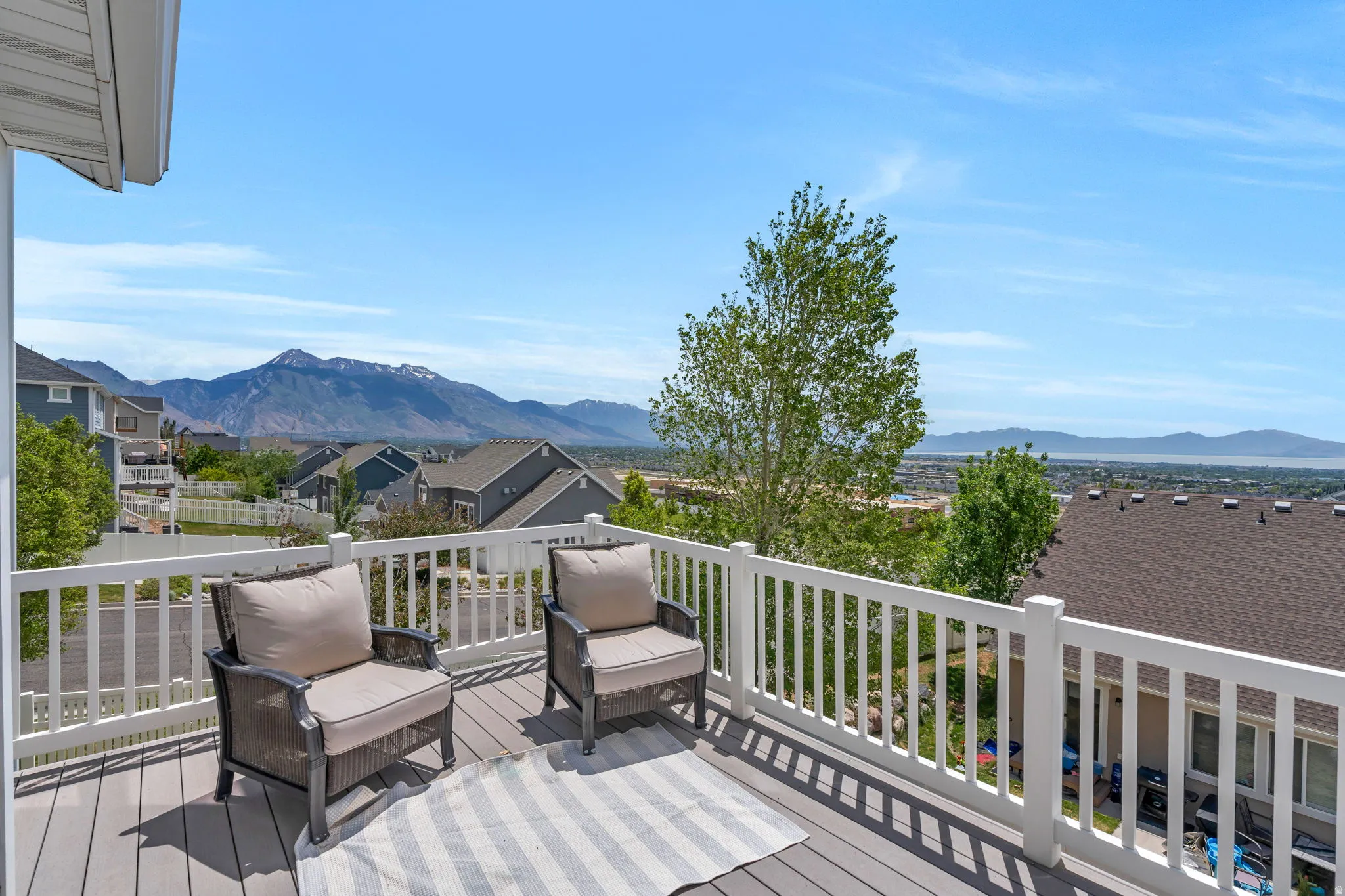 Spacious outdoor deck featuring composite decking, white railing, and a mountainous backdrop