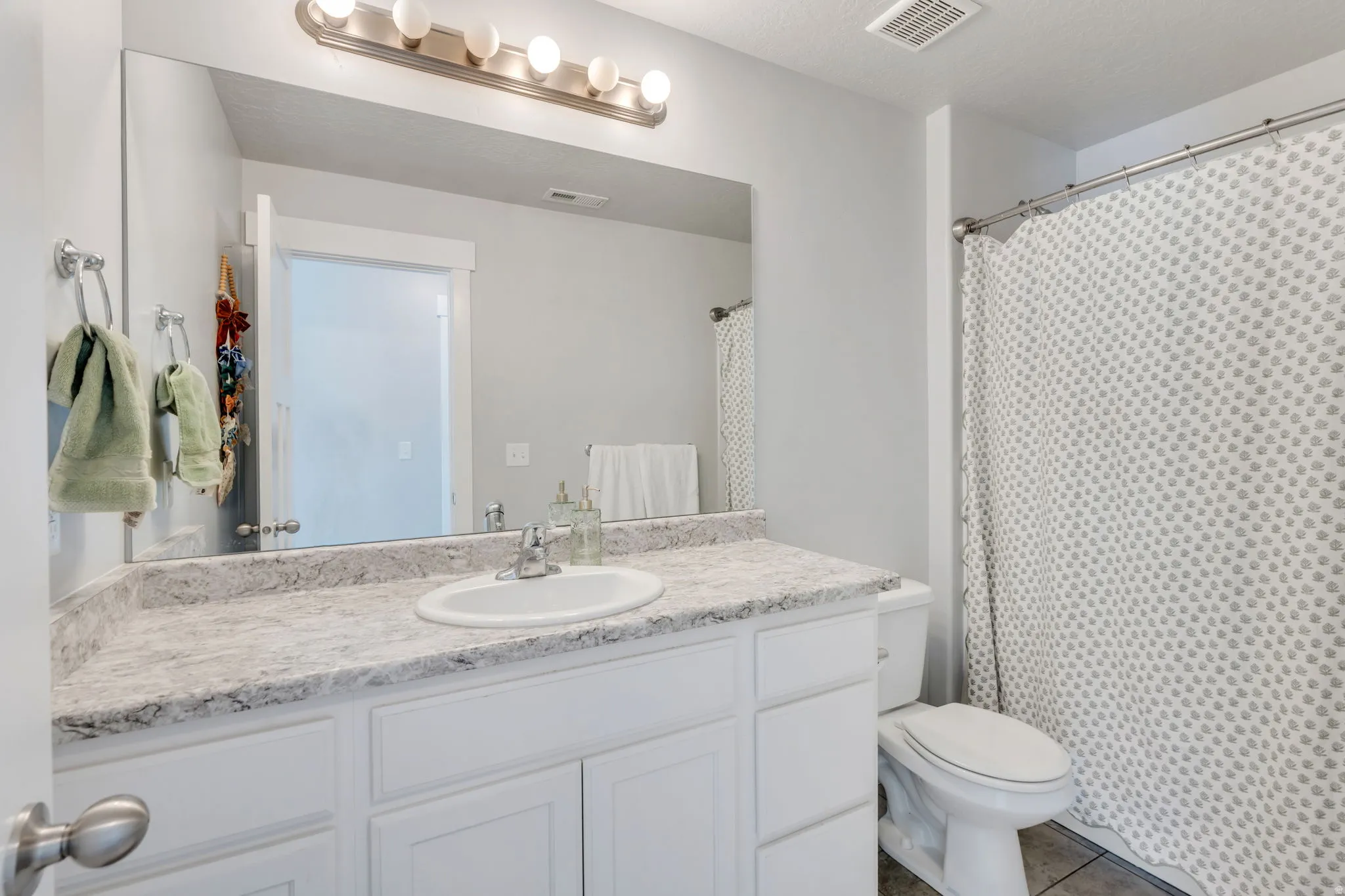Bathroom featuring a white vanity with integrated sink, a speckled light-toned countertop, and a brushed nickel light fixture