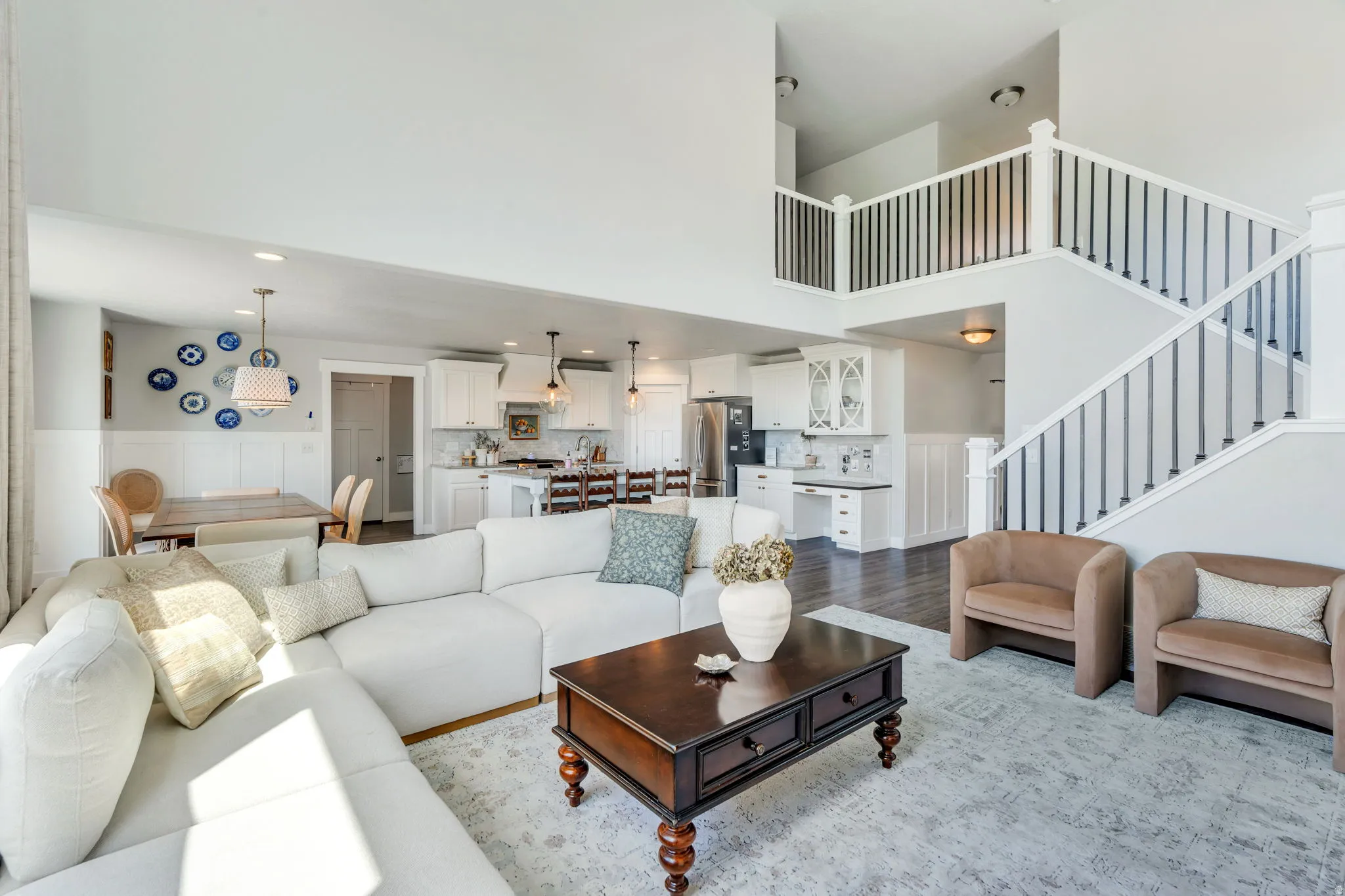 Open-concept living space featuring a two-story ceiling, a staircase with black metal balusters, and wood-finish flooring