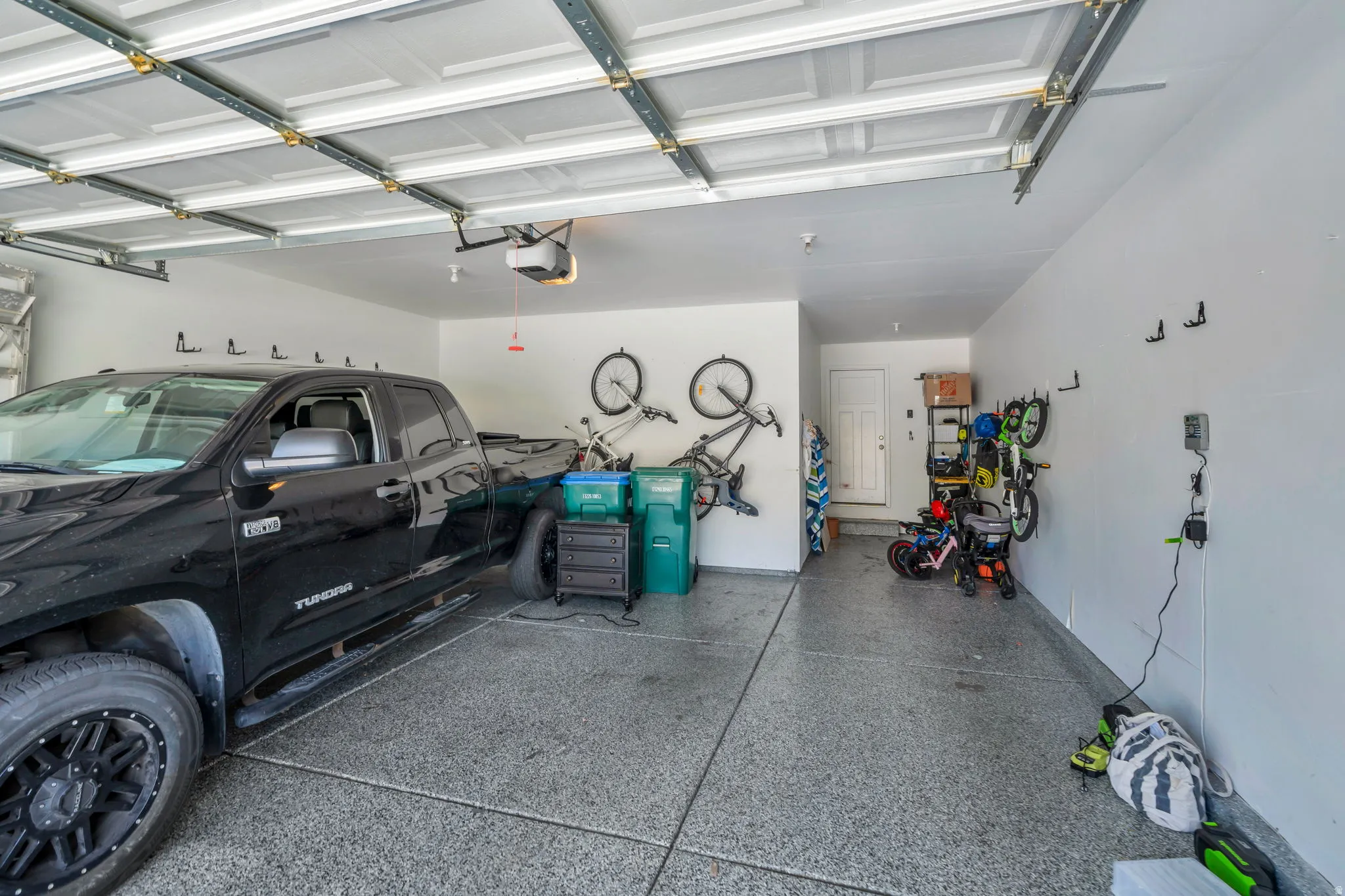 Two-car garage featuring a speckled epoxy floor, overhead garage door with automatic opener, white walls, and a side access door