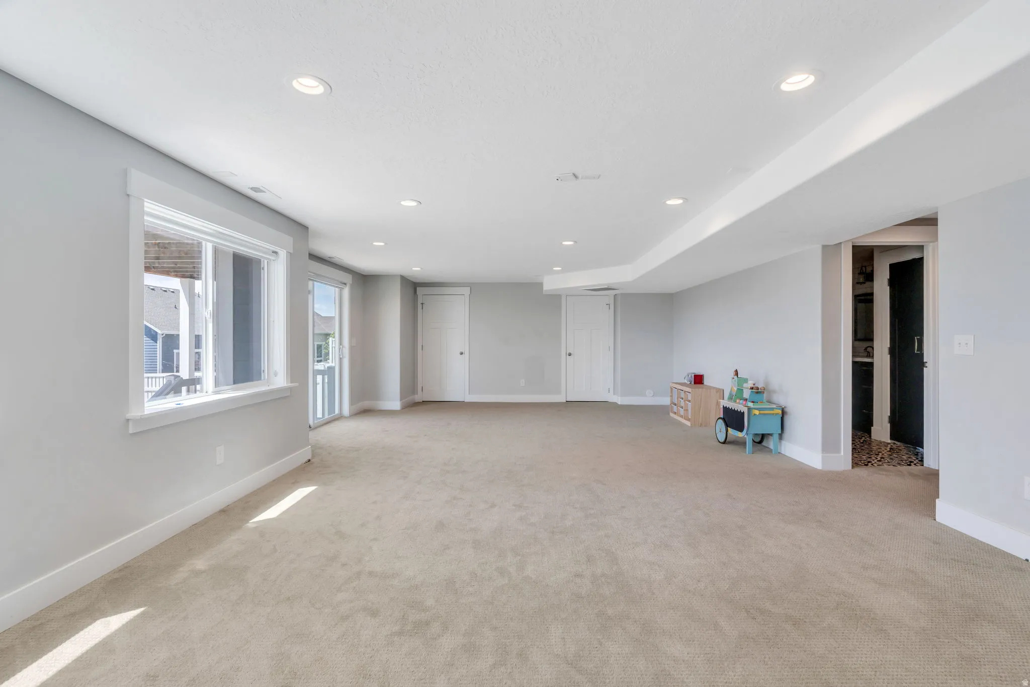 Spacious room featuring neutral carpeting, recessed lighting, and light gray walls