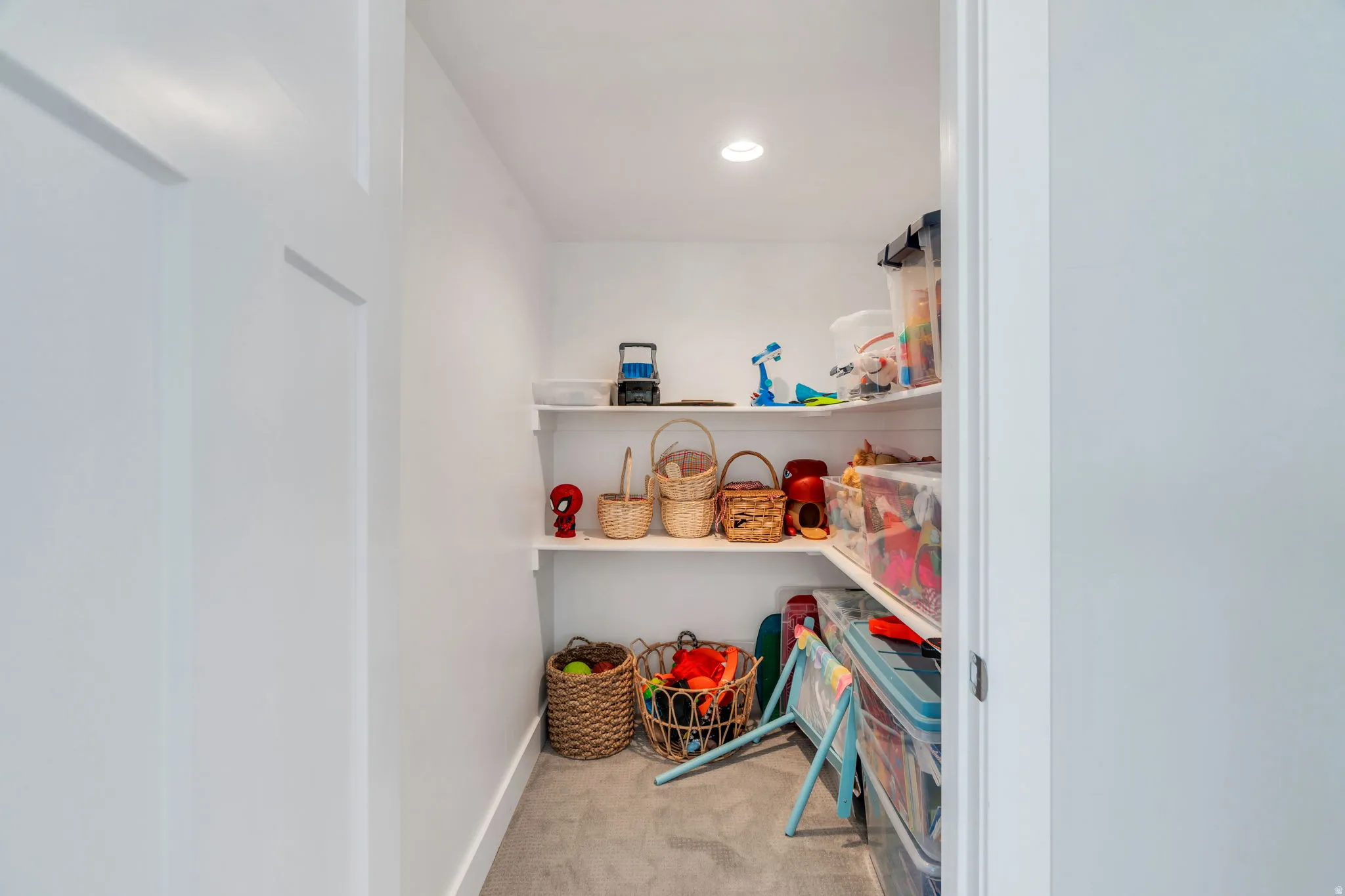 Expansive storage closet featuring built-in shelving, white painted walls, recessed lighting, and a concrete floor