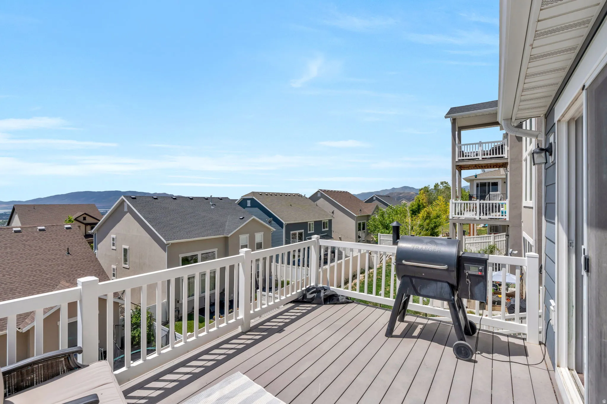 Spacious outdoor deck featuring composite wood-finish decking, white railings, and direct exterior access