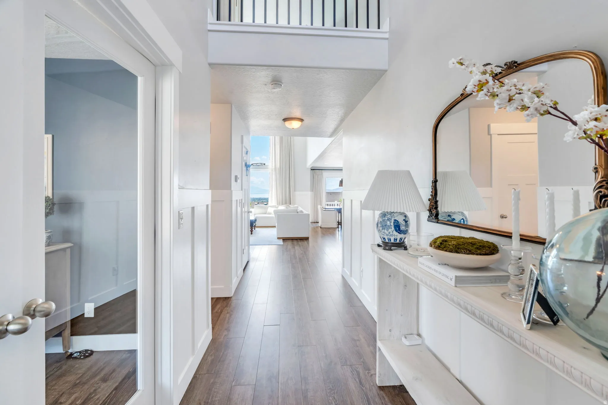 Hallway featuring wood-finish flooring, white wainscoting, and a built-in console table