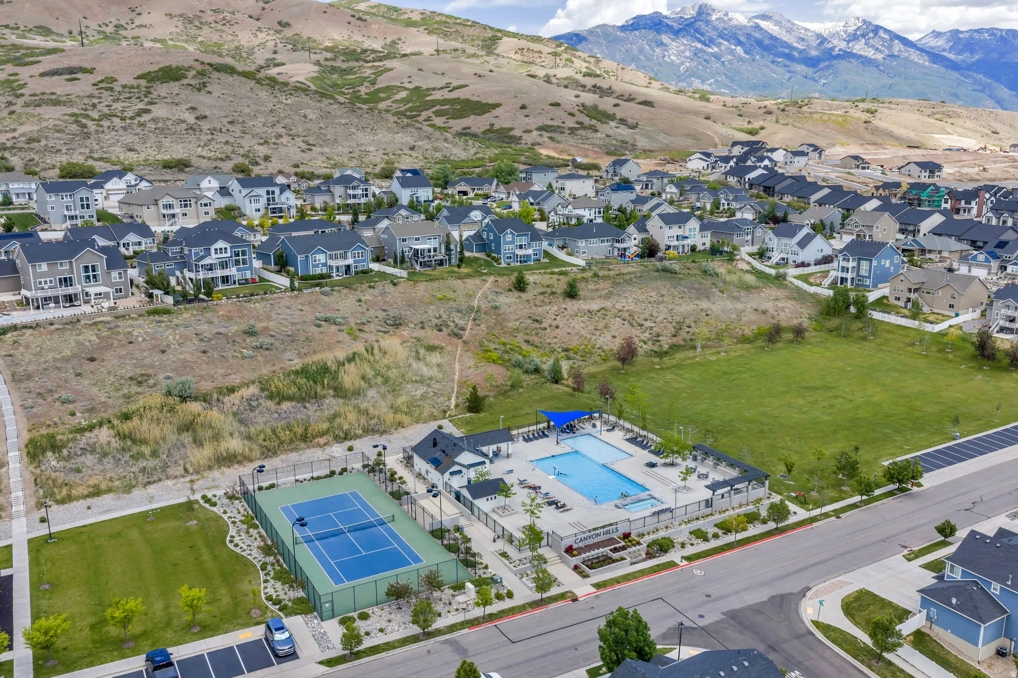 Community amenities featuring a swimming pool, tennis court, and expansive green space