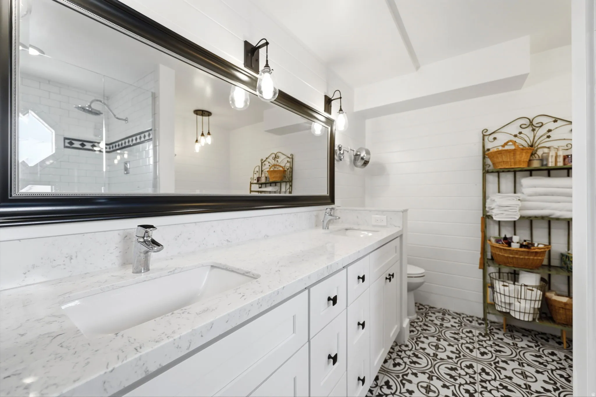 Dual vanity featuring a white countertop with integrated sinks, black hardware, and an expansive framed mirror