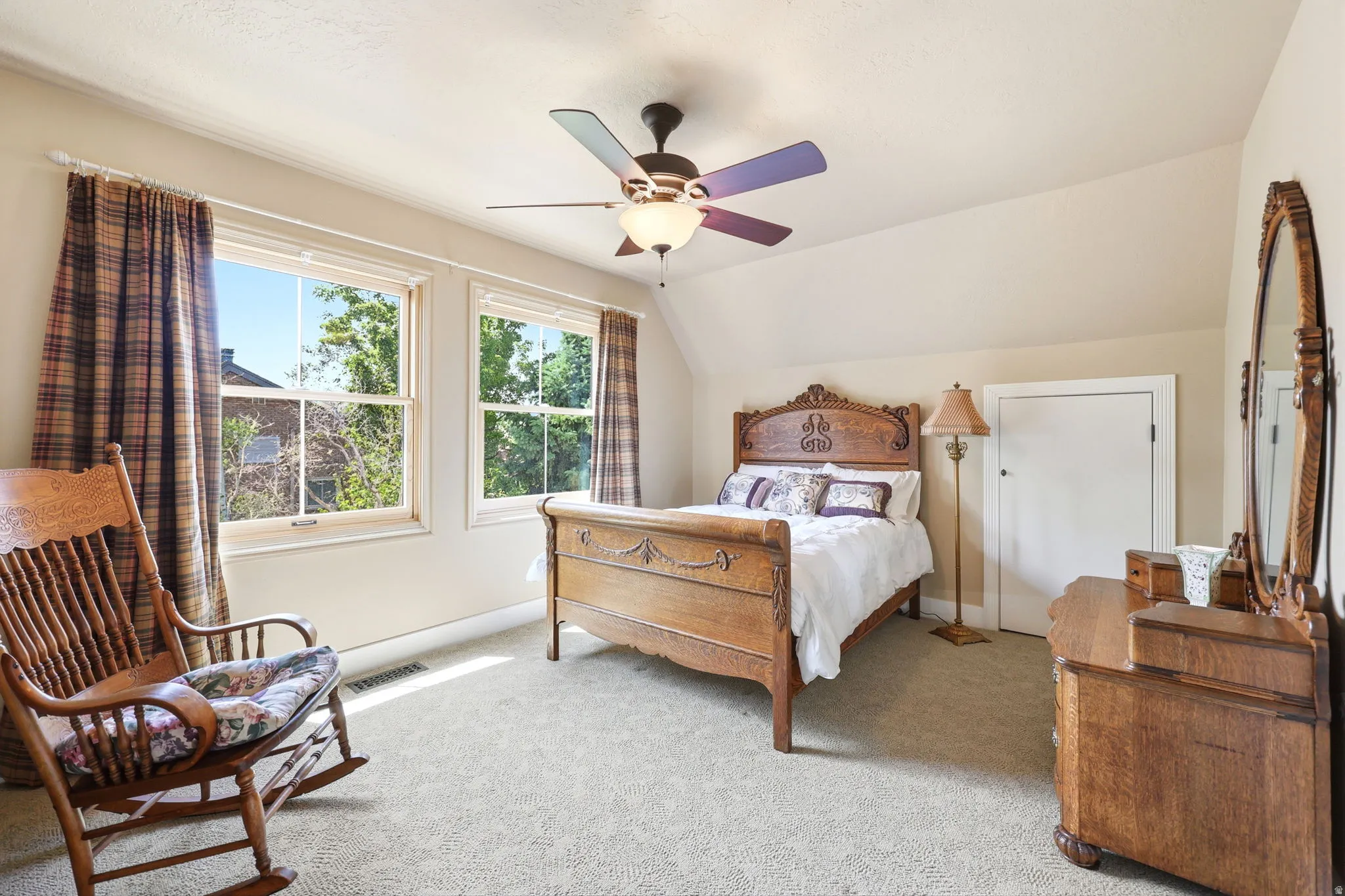 Bedroom featuring two double-hung windows, wall-to-wall carpeting, an angled ceiling, and a ceiling fan with integrated lighting