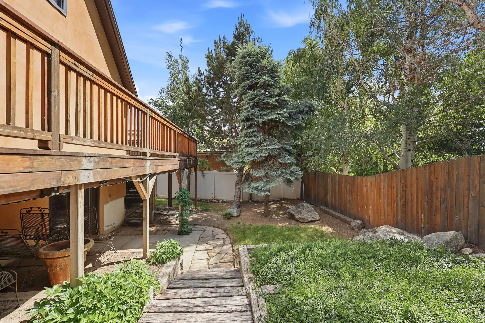 Multi-level wood deck structure with a full-length wooden railing and a stucco exterior