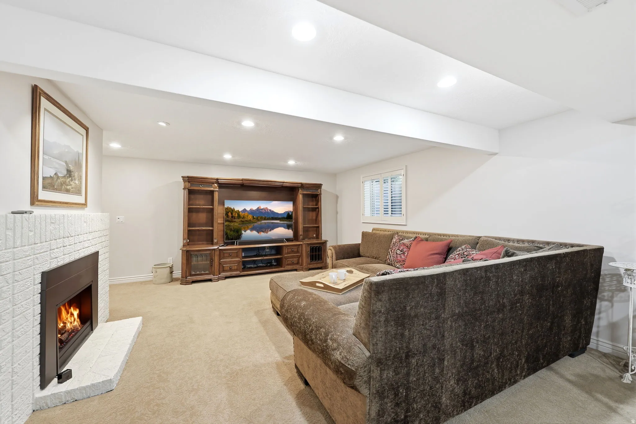 Living area featuring a white brick fireplace with a tile hearth, recessed lighting, and neutral carpeting