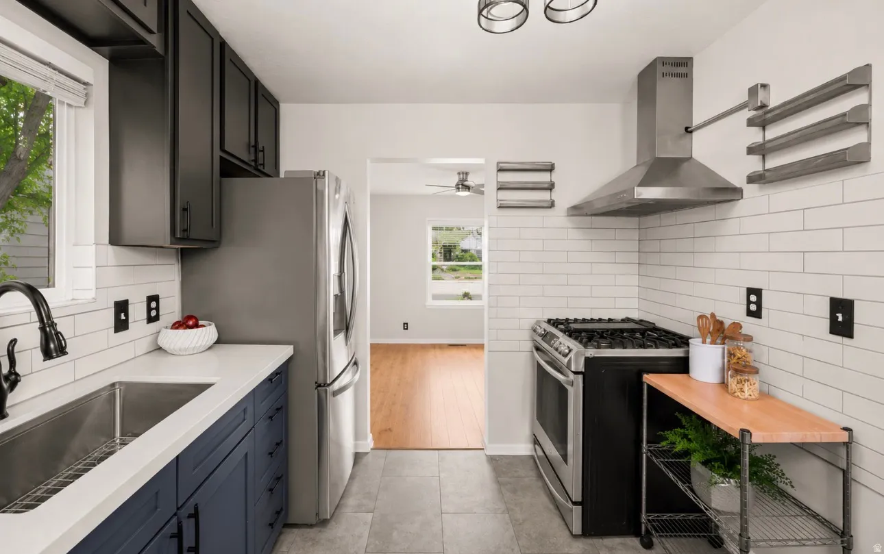 Contemporary kitchen featuring stainless steel appliances, a gas range with a matching range hood, and white subway tile backsplash
