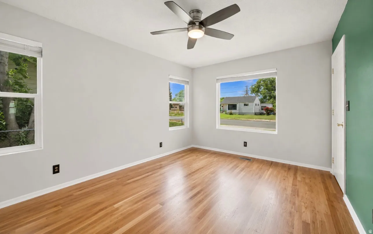 Room featuring wood-finish flooring, light grey walls, and a green accent wall