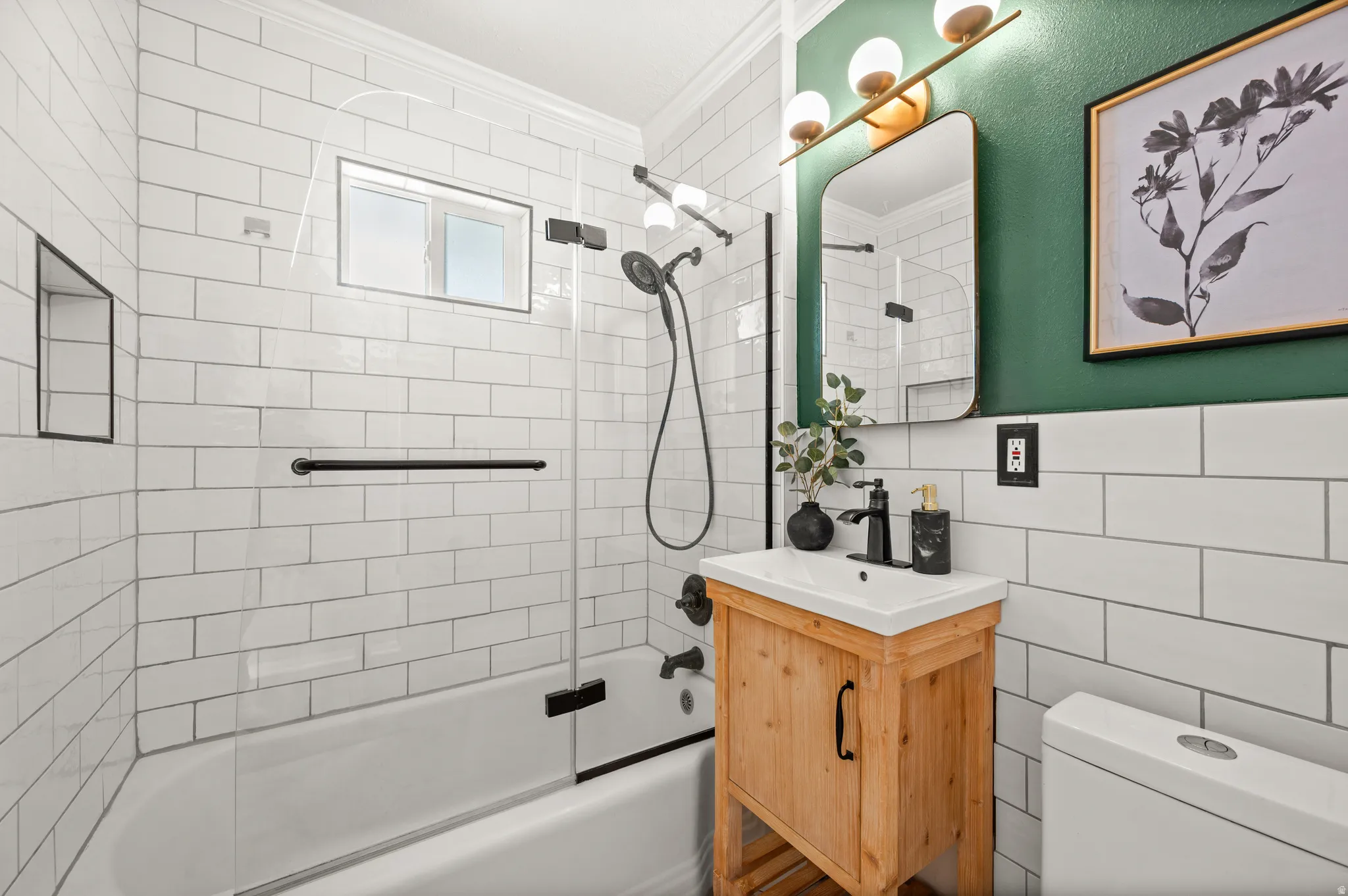 Bathroom featuring a wood-finish vanity with an integrated white sink, brushed bronze faucet, and a rectangular mirror